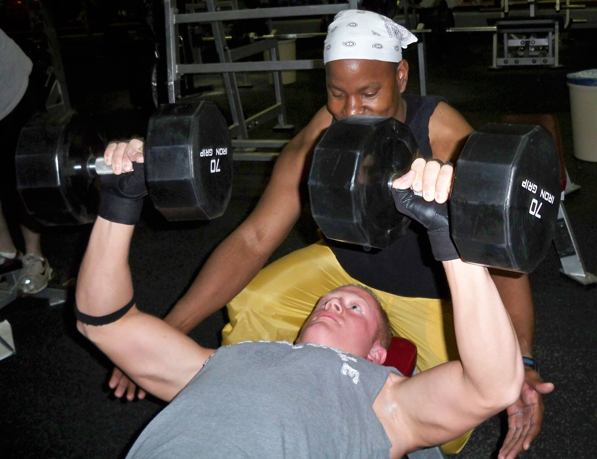 WHITEMAN AIR FORCE BASE, Mo. – Capt. Michael Boswell, 509th Logistics Readiness Squadron and WAFB bodybuilding coach, spots Airman 1st Class Stephen Linch, 509th Bomb Wing Public Affairs, as he performs dumbbell presses Aug 13. Airman Linch is one of 12 WAFB Body Building Team members training for upcoming competitions.  (U.S. Air Force photo/Stephanie Fowler)