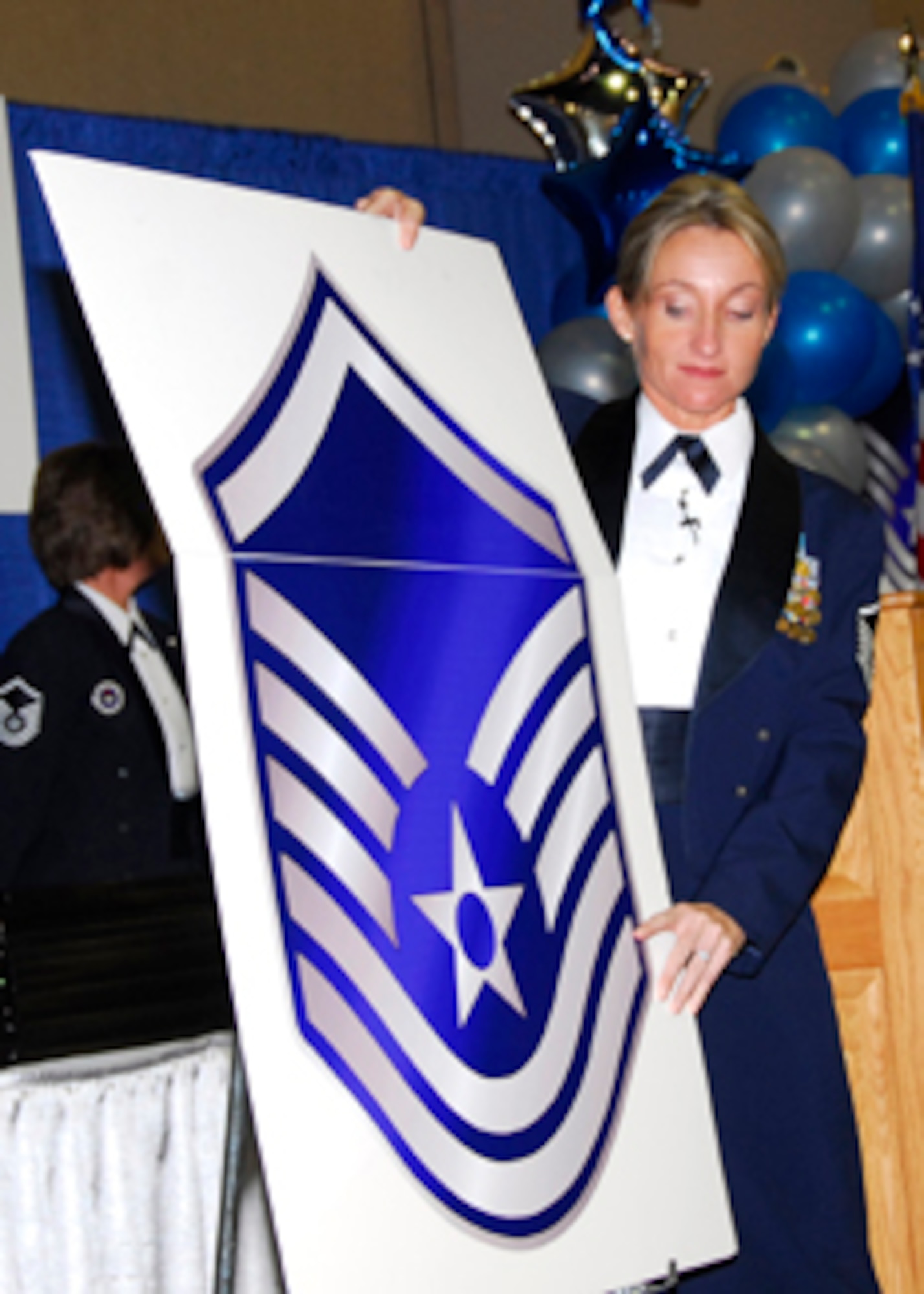 Master Sgt. Linda McCoy "raises the roof" on a set of tech sergeant stripes at the Senior NCO Induction Ceremony Aug. 8 at the Multi-Purpose Events Center in Wichita Falls. (U.S. Air Force photo/Harry Tonemah) 