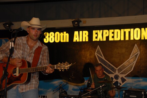 SOUTHWEST ASIA -- King Cone, lead vocalist and song writer, belts out a song on stage at the 380th Air Expeditionary Thirsty Camel Pavilion Aug. 13.  King stated he felt like he was wearing a bathing suit, referencing his sweat-drenched clothing. Peter Piper (background), drummer, beats out the accompanying rhythm. (U.S. Air Force Photo/Tech. Sgt. Christopher A. Campbell) (released)