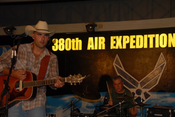 SOUTHWEST ASIA -- King Cone, lead vocalist and song writer, belts out a song on stage at the 380th Air Expeditionary Thirsty Camel Pavilion Aug. 13.  King stated he felt like he was wearing a bathing suit, referencing his sweat-drenched clothing. Peter Piper (background), drummer, beats out the accompanying rhythm. (U.S. Air Force Photo/Tech. Sgt. Christopher A. Campbell) (released)