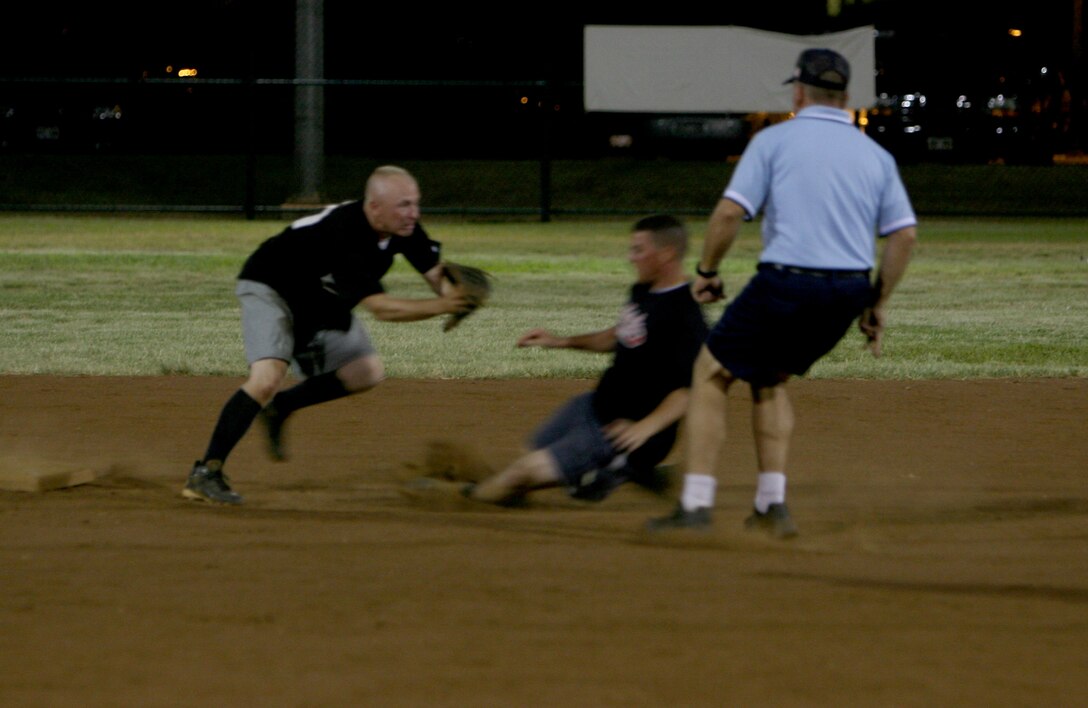 Talal Hafez, 3rd Radio Battalion utility player, slides past Christopher Oliger, Provost Marshall's Office Law Dawgs shortstop,  during the 2008 Intramural Softball League quarter final playoff game at Annex field Aug. 15.