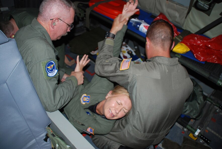 Only pretending...Staff Sgt. Melissa Calabrese is restrained by other members of the 932nd Aeromedical Evacuation Squadron during a training flight aboard a KC-135 over the Caribbean. Sergeant Calabrese was playing the role of a patient with severe emotional problems.  The training helped the aircrew know how to handle a variety of emergencies while in flight.  Photo by Tech. Sgt. Gerald Sonnenberg