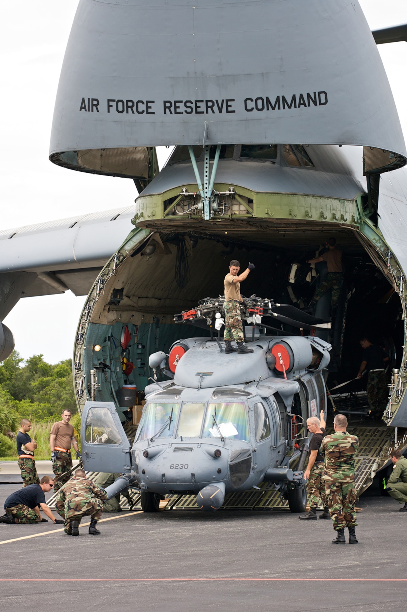 CAPE CANAVERAL AIR FORCE STATION, Fla., -- Air Force Reservists from the 920th Rescue Wing at Patrick Air Force Base, Fla., prepare two HH-60G Pave Hawk helicopters by folding various moving parts for transport onto a C-5 Galaxy aircraft.  The C-5 airlifted the helos to the southern Arizona desert where helicopter aircrews and maintenance personnel trained July 12-25 for the toughest flying conditions in the world - Afghanistan. Not only is the country notorious for craggy terrain, but its known for impromptu dust storms, no cultural lighting and some of the highest mountains and steepest valleys.  (U.S. Air Force Photo/Tech. Sgt. Jeremy Allen)