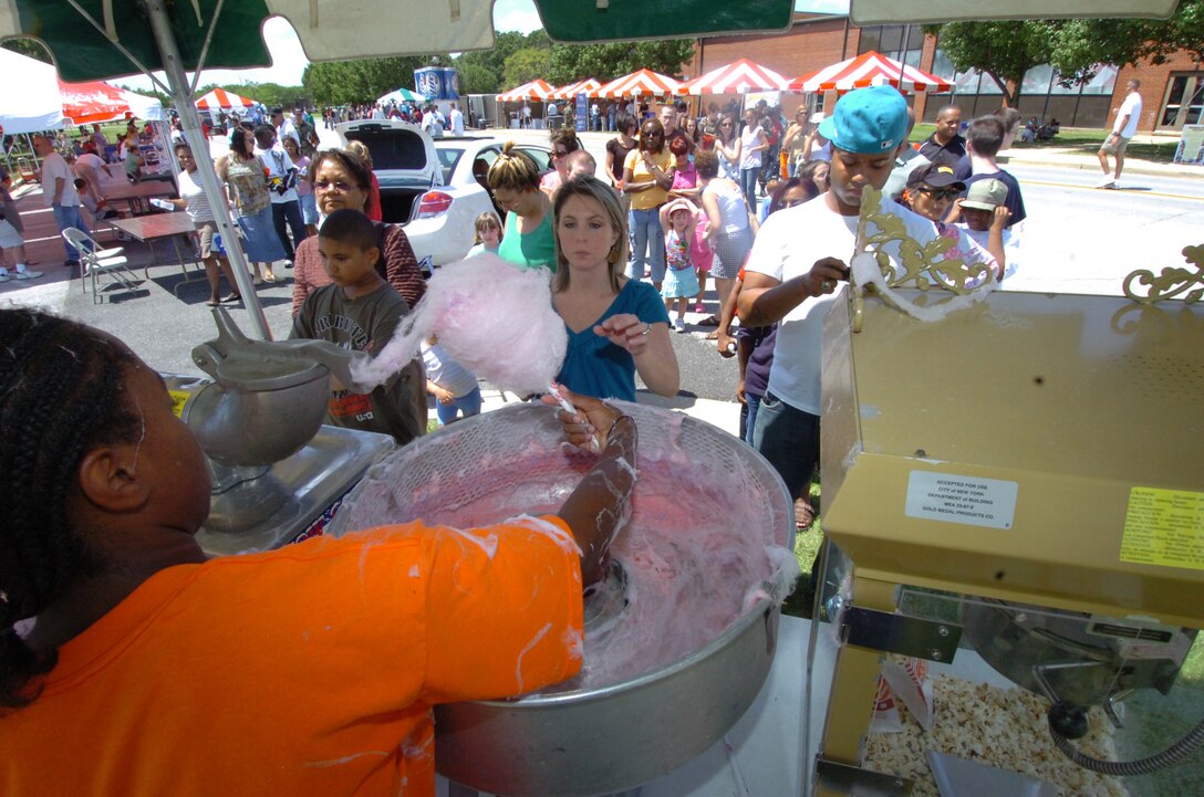 An Andrews youth swirls up free cotton candy for an endless line of Andrews members and their families during the Annual Family Fun Day event held near the West Fitness Center Aug. 8.  Hosted by the 316th Services Squadron, members were treated to free food, beverages and several fun activities. More than 4,000 military members, civilians and their families attended the day-long event. The annual event is held to thank base employees and their families.