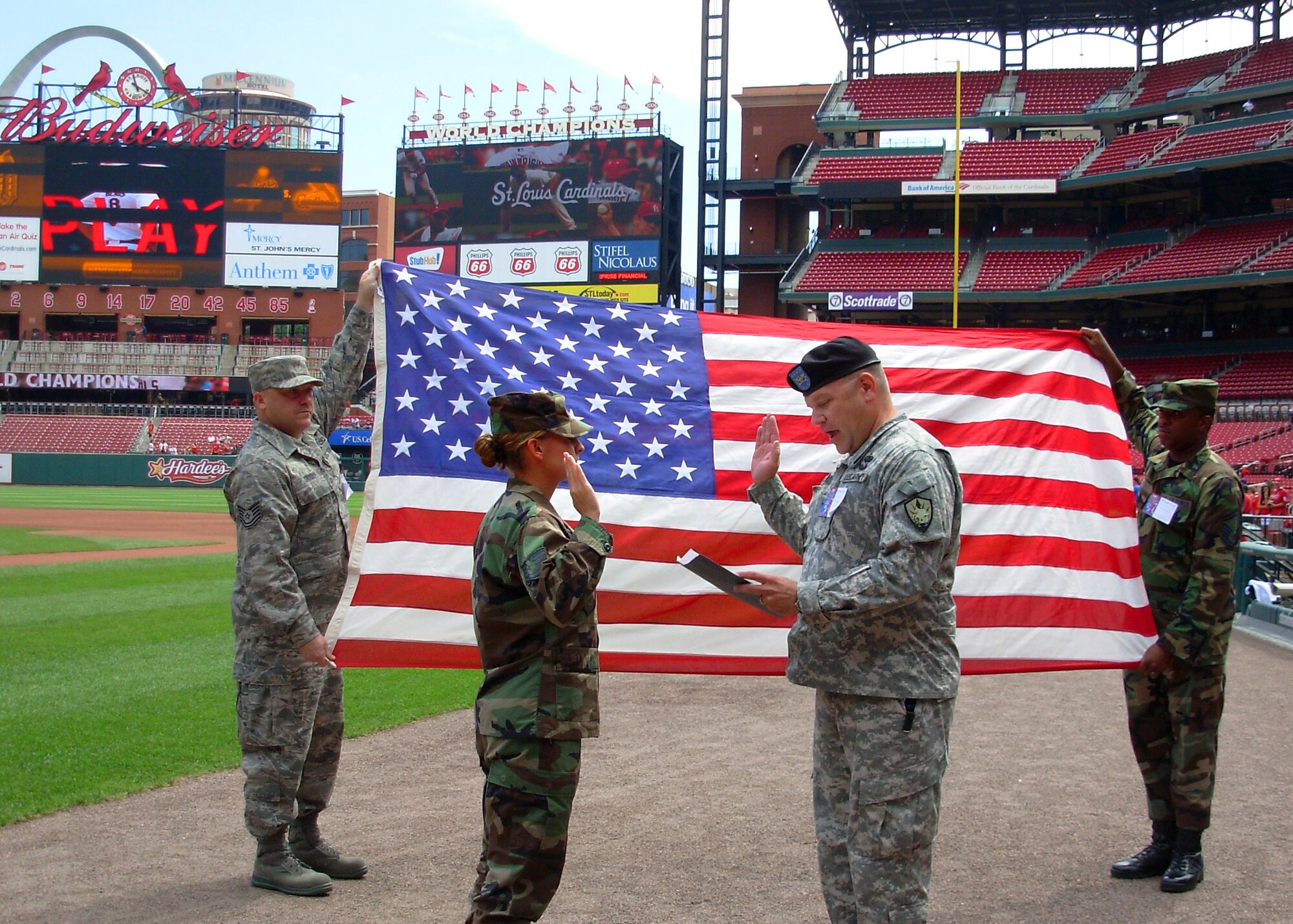 SCOTT AIR FORCE BASE, Ill. -- Col. Robert Johnson (right) reads the oath of enlistment to Tech. Sgt. Daniella Benson as she reenlists during a ceremony Aug. 7 at Busch Stadium.  Sergeant Benson says she is a life-long St. Louis Cardinals fan and requested the unique setting for her ceremony.  Holding the U.S. flag are Tech. Sgt. Brian Dryden and Senior Master Sgt. Arnold White.  All are members of the U.S. Transportation Command. 
photo by Kara Kessel