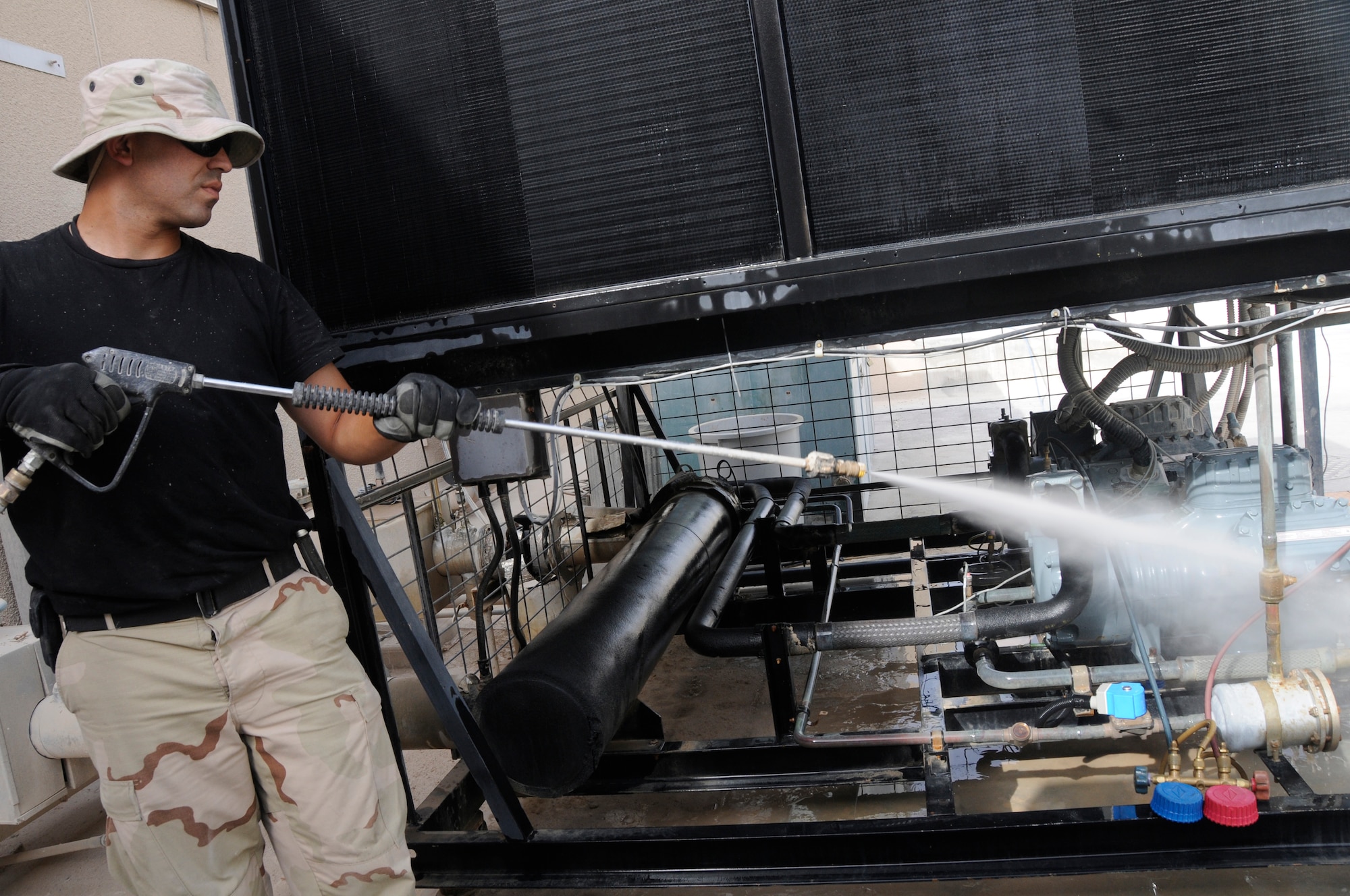 Tech. Sergeant Christopher Tilstra, heating ventilation air conditioning and refrigeration craftsman with the 379th Expeditionary Civil Engineer Squadron, sprays an air conditioning unit with a pressure sprayer to remove dirt and dust Aug. 14, 2008, at an undisclosed air base in Southwest Asia. The 379th ECES is responsible for providing mission critical and comfort cooling for equipment and personnel deployed in scorching desert heat. Sergeant Tilstra, a native of Hawarden, Iowa, is deployed from Grand Forks Air Force Base, N.D., in support of Operations Iraqi Freedom, Enduring Freedom and Joint Task Force-Horn of Africa. (U.S. Air Force photo by Staff Sgt. Darnell T. Cannady/Released)