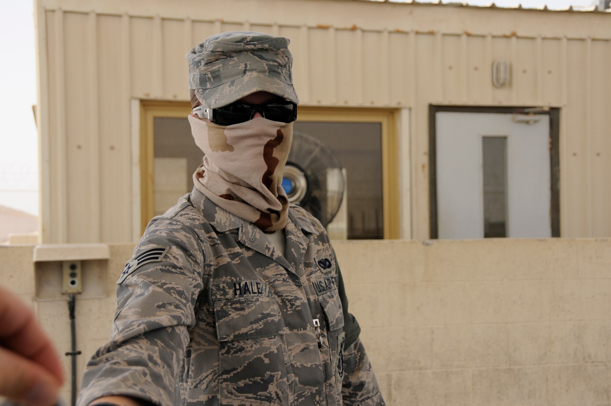 Senior Airman Lindsey Hale, 379th Expeditionary Security Forces Squadron, bundles up as protection against swirling dust conditions Aug. 14, 2008, at an undisclosed air base in Southwest Asia.  Airman Hale, deployed from Davis-Monthan Air Force Base, Ariz., checks identification cards prior to allowing entry into the housing area. She is deployed in support of Operations Iraqi Freedom, Enduring Freedom and Joint Task Force-Horn of Africa.  (U.S. Air Force photo by Tech. Sgt. Michael Boquette/Released)