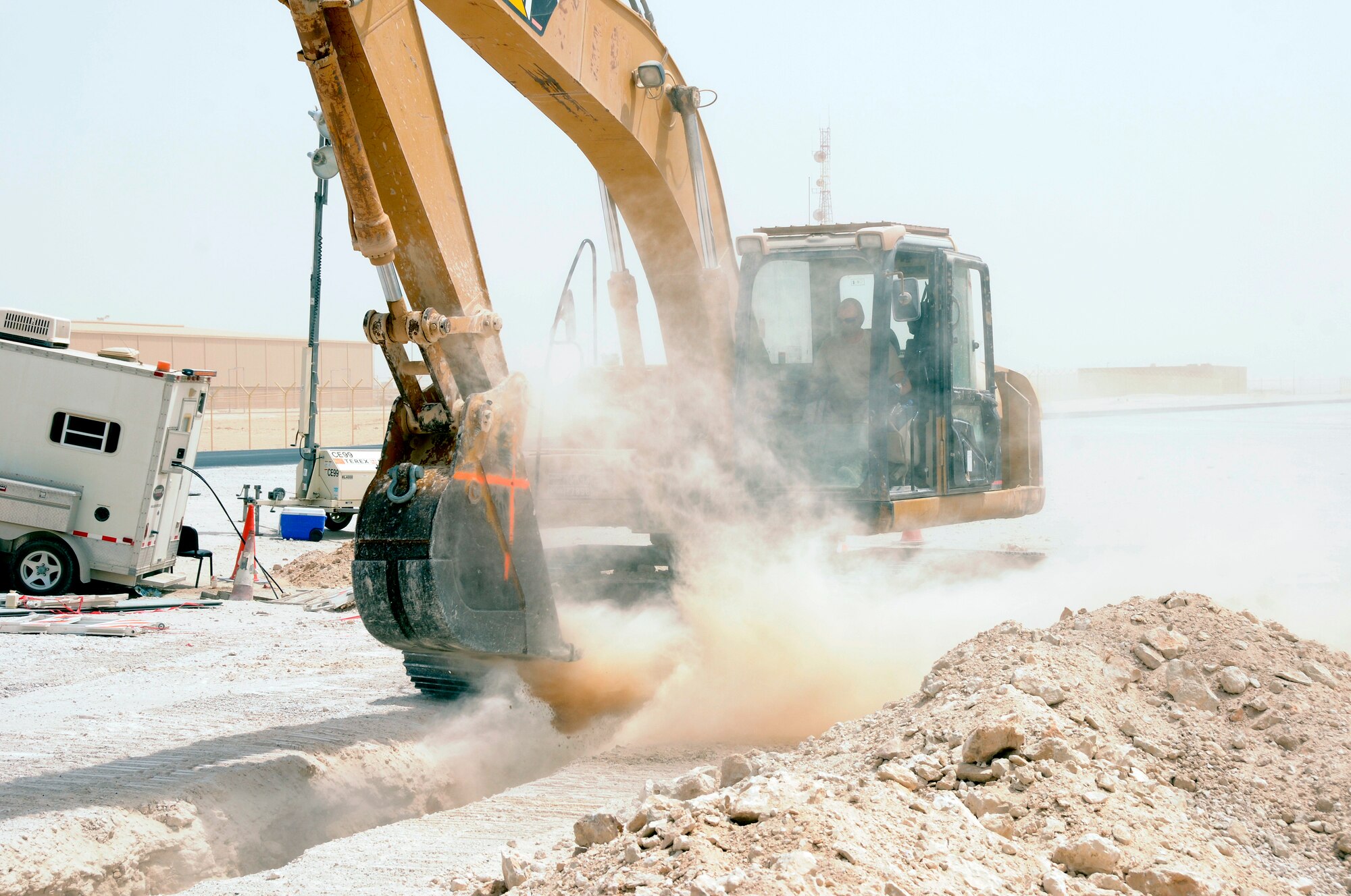 Tech. Sgt. Camon Tucker, 379th Expeditionary Civil Engineer Squadron creates a dust storm while digging a trench Aug. 13, 2008, at an undisclosed air base in Southwest Asia.  Sergeant Tucker, a pavement and construction operator clears the trench that will be used for laying communication cable for the Royal Air Force unit here. Sergeant Tucker hails from Albuquerque, N.M. and is deployed from F. E. Warren Air Force Base, Wyo., in support of Operations Iraqi Freedom, Enduring Freedom, and Joint Task Force - Horn of Africa.  (U.S. Air Force photo by Tech. Sgt. Michael Boquette/Released)