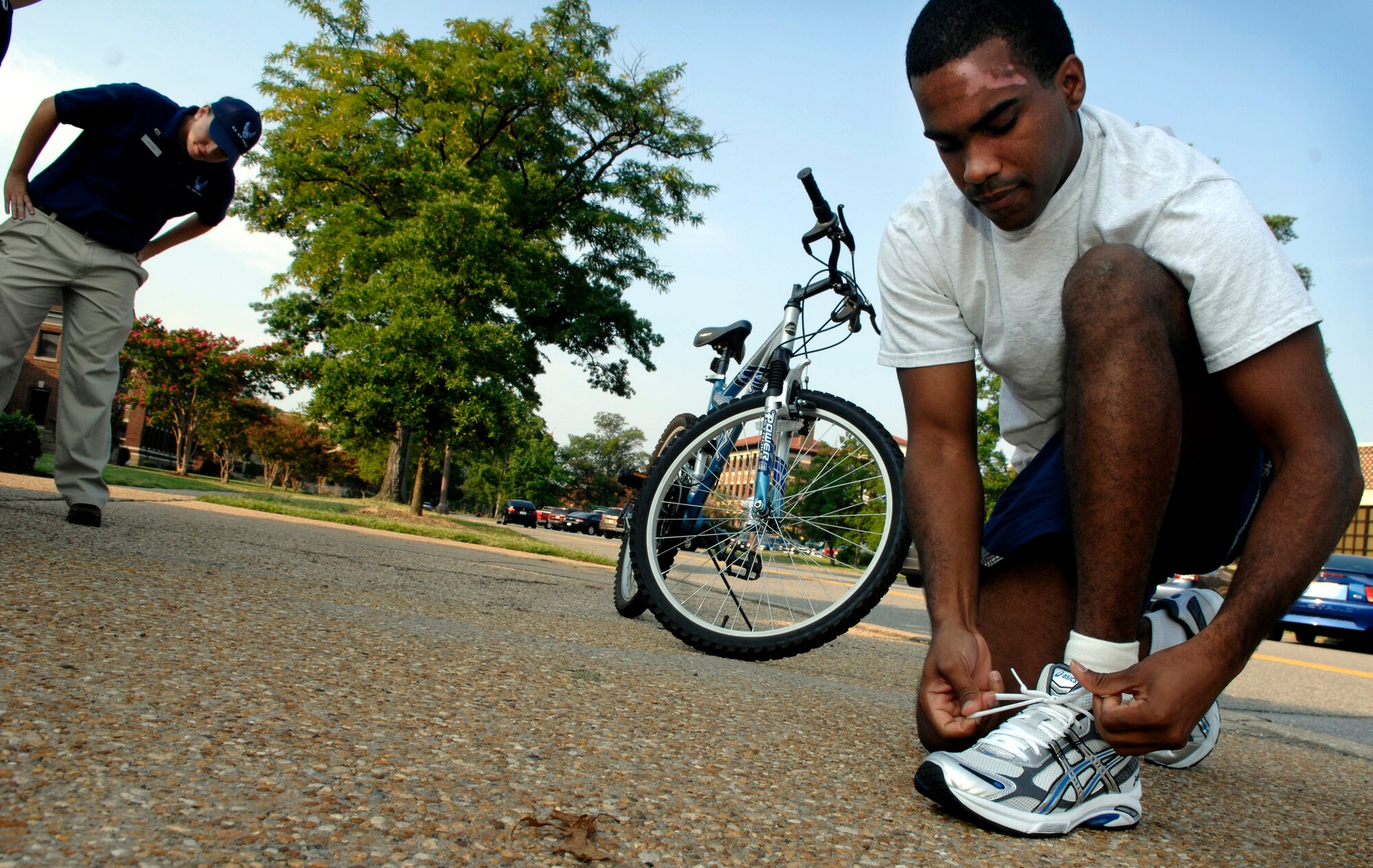 LANGLEY AIR FORCE BASE, Va. --  Airman 1st Class Brendan Davis, 1st Aerospace Medicine Squadron, laces his shoes as Airman 1st Class Catherine Leahy, 1st Force Support Squadron, examines other participants before a duathlon Aug. 15.  A duathlon is an eight mile exercise designed to challenge each participant's physical endurance with cycling and running.  The 1st FSS organizes an event monthly to continue encouraging physical fitness as the Air Force exercises the fit to fight mentality.  (U.S. Air Force photo/Senior Airman Vernon Young)