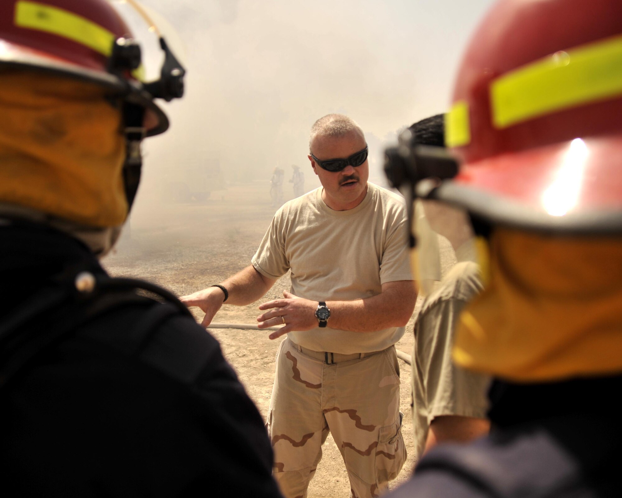 8/14/2008 - BAGHDAD, Iraq -  Tech. Sgt. Don Edgar, 447th Expeditionary Civil Engineer firefighter, instructs an Iraqi firefighters about how to properly advance on a structure fire. The Airman firefighters, from near-by Sather Air Base, assisted the Iraqi fire department with live-burn training in a special secure compound for the families of Iraqi workers who assist with the rebuilding of their country. The Iraqi firefighter?s identities are concealed to protect them from insurgent activities. Sergeant Edgar is a New York Air National Guard Airman deployed from the 174th Fighter Wing in Syracuse. When he is not wearing his Air Force firefighter uniform, Sergeant Edgar serves as a state corrections officer.(U.S. Air Force Photo by Master Sgt. Brian Davidson)