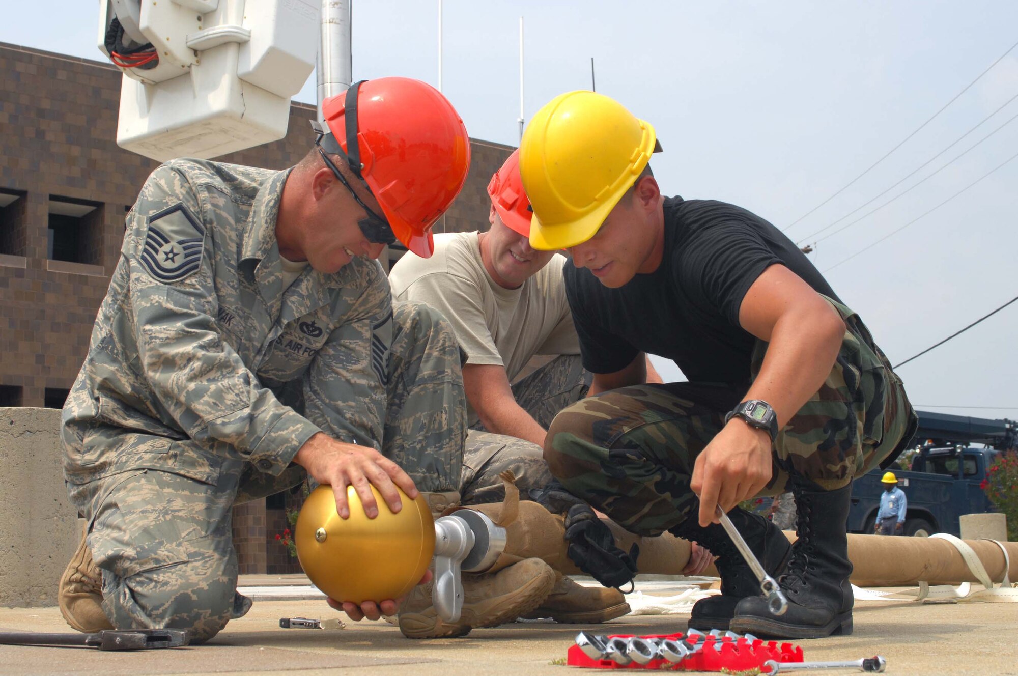 SHAW AIR FORCE BASE, S.C. -- Master Sgt. Roger Nowak and Airman 1st Class Brian King, 20th Civil Engineer Squadron, attach a finial ornament to the top section of the flagpole as Staff Sgt. Josh Miller, 20th CES, helps hold it steady. The flagpole is being installed in a newly renovated area in front of the 20th Fighter Wing Headquarters building Aug. 12. (U.S. Air Force photo/Senior Master Sgt. Brad Fallin)