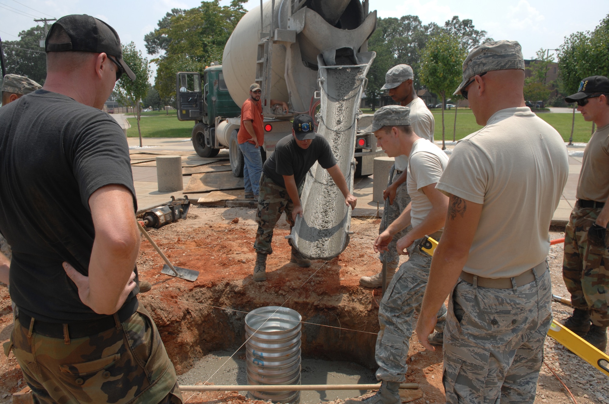 SHAW AIR FORCE BASE, S.C. -- Staff Sgt. David Mitchell (middle), 20th Civil Engineer Squadron "Dirtboyz" heavy equipment operator, guides wet concrete for a flag base August 5. The "Dirtboyz" are constructing a new Shaw flag for the 20th Fighter Wing headquarters. The project is scheduled for completion August 15.   (U.S. Air Force photo/Staff Sgt. Nathan Bevier)