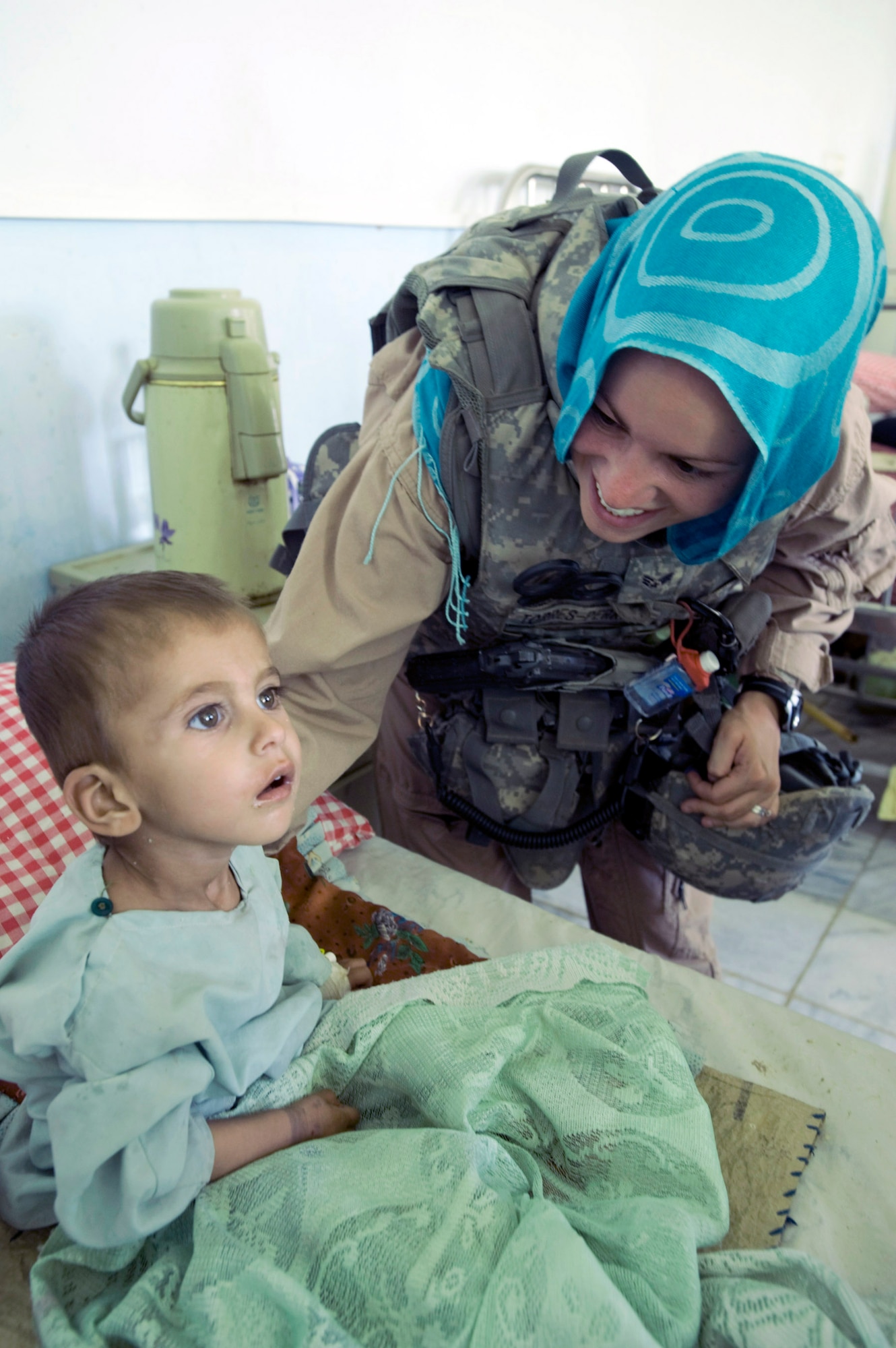 Senior Airman Felicita Torres-Perkins, a member of the Zabul Provincial Reconstruction Team, comforts a young Afghan girl Aug. 10 at the Qalat Hospital in Qalat, Afghanistan. She wears the scarf to honor the customs of this conservative region of the country. (U.S. Air Force photo/Master Sgt. Keith Brown)
