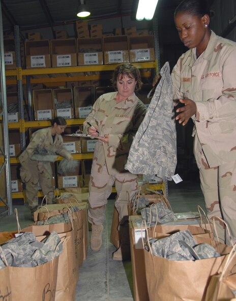 SOUTHWEST ASIA -- Senior Airman Xavier Taggart, places uniform trousers into a bag as Tech. Sgt. Ann Williams takes inventory of the items. Airman 1st Class Shawna Wilson also places uniform items into bags for deployed personnel here. The bags are made up according to lists of members who will still be at this location after Oct. 1. (U.S. Air Force photo/Tech. Sgt. Christopher A. Campbell) (released)