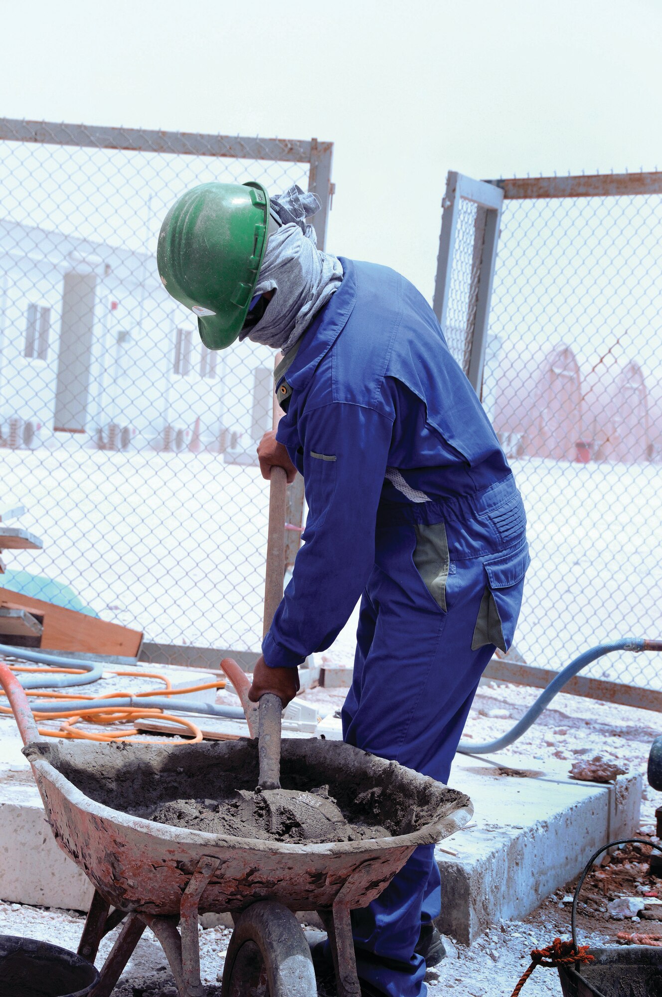 A contract worker mixes a wheelbarrow of cement  during the construction of a new permanent restroom facility. The facilities, called cadillacs, will eventually replace current ones. Until that happens the semi-permanent ones will undergo renovation as part of  the Grand Slam Campaign. (U.S. Air Force photo by Tech. Sgt. Michael Boquette)