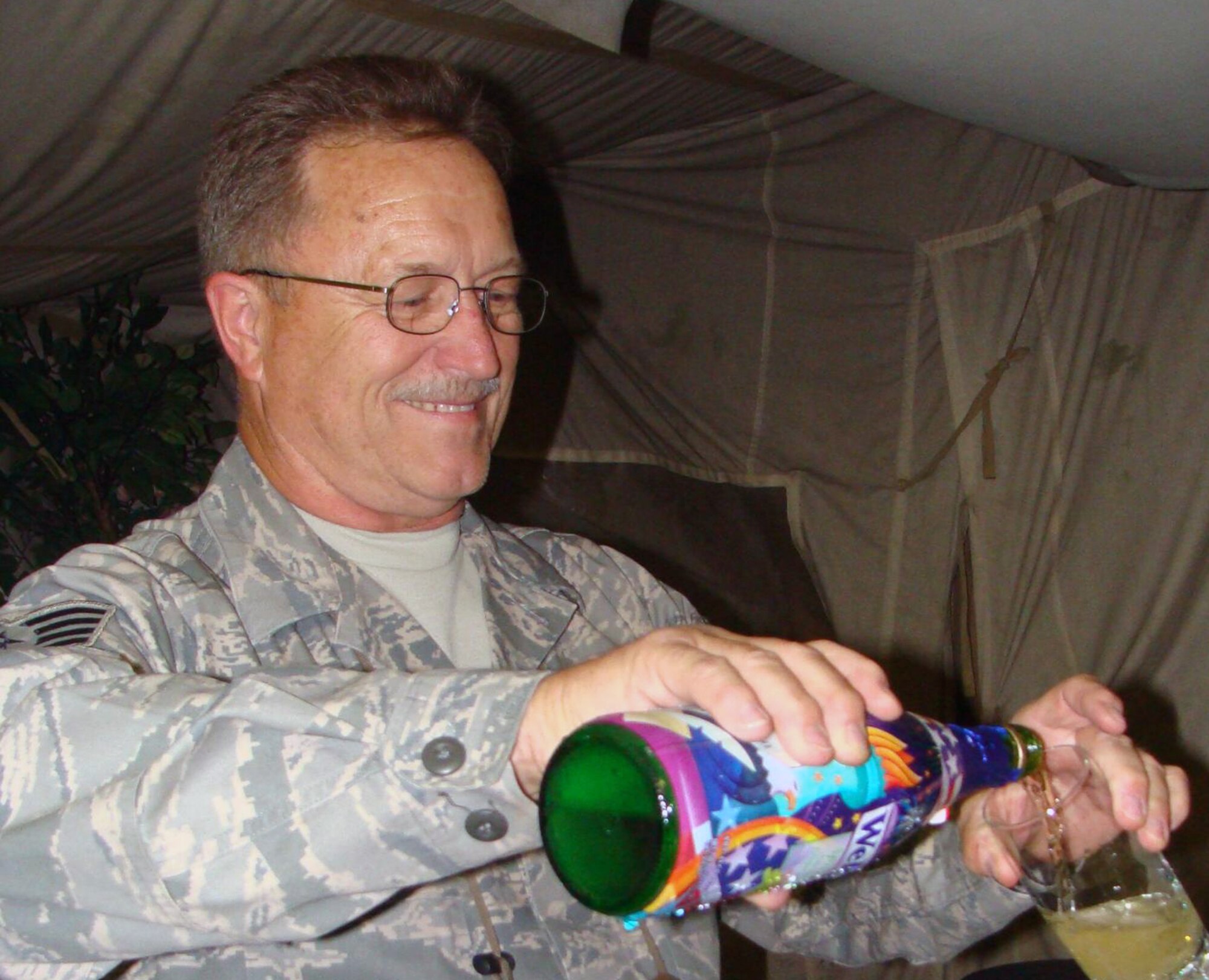 MANAS AIR BASE, KRYGYZ REPUBLIC--Staff Sgt. Albert Jensen is all smiles as he pours sparkling grape juice following his marriage to long time sweetheart, Charlene Kehaualani Meyer, who is in Hawaii. The couple married through a double proxy ceremony, Aug. 8, which spanned 16 time zones and 16,000 miles with the bride in Hawaii, chaplain in Montana, and groom in the Kyrgyz Republic. (Air Force courtesy photo) 