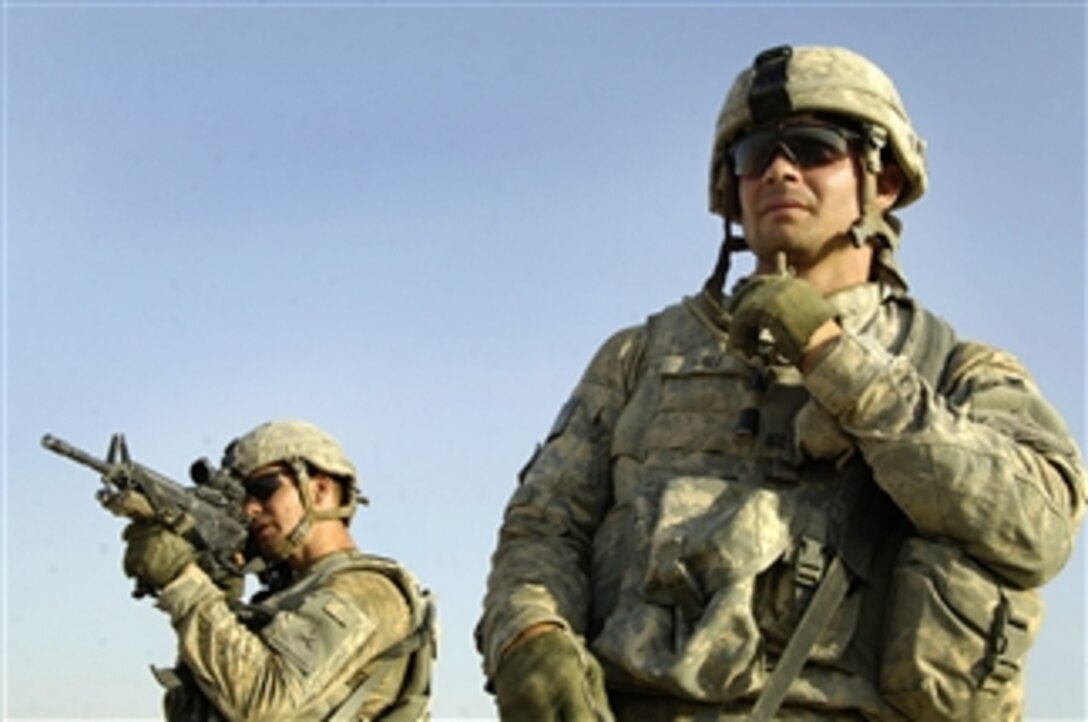 U.S. Army Spc. Patrick Hall looks on as Staff Sgt. David Graham scans the countryside for suspicious activity during a clearing mission near a canal outside of Tamuz, Iraq, on Aug. 9, 2008.  U.S. soldiers from 2nd Brigade Combat Team, 1st Armored Division conducted the operation to search for signs of extremist activity in the area.  