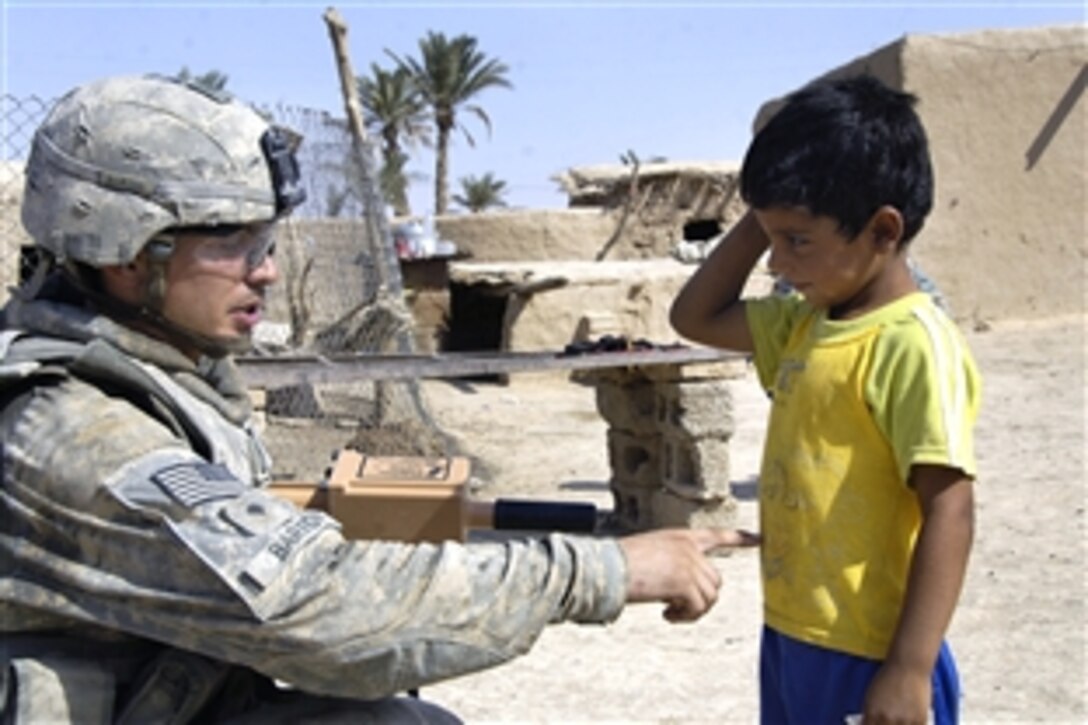 U.S. Army Spc. Paul Barton takes a break to talk with an Iraqi boy about the design on his T-shirt during a village assessment mission in Tamuz, Iraq, Aug. 10, 2008. Barton is assigned to the combat observation liaison team assigned to Task Force 1. 