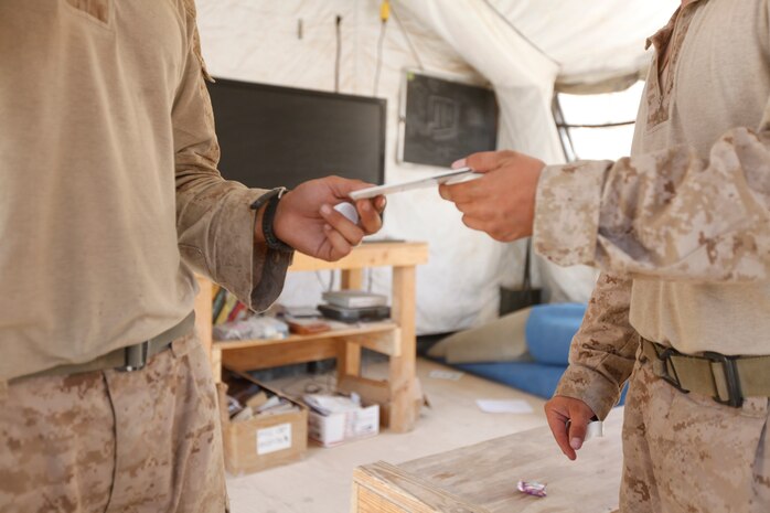 Petty Officer 2nd Class Andrew S. Lovick, the religious program specialist for 3rd Battalion, 1st Marine Regiment, hands Lance Cpl. Joseph L. Montoya, a rifleman with Company L, 3/1, the disk with his message to his daughter and wife at Patrol Base Koshtay, June 19.  After finishing the recording the Marine receives the disk and an envelope that he can send his loved ones for free.