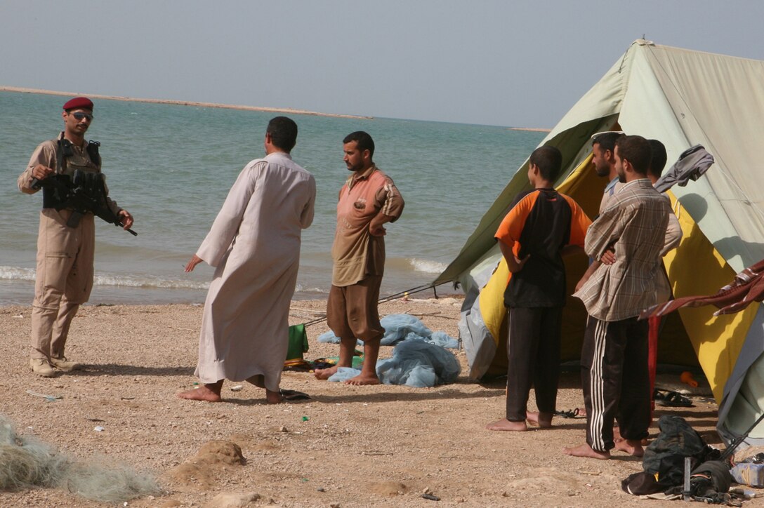 SADAMIYAH PENINSULA, Iraq (August 14, 2008) – An Iraqi soldier with Iraq’s 1st Battalion, 2nd Brigade, 1st Iraq Army Division, talks with local fishermen as he patrols through a fish market Aug. 15, during a 72-hour Iraqi-led sweep operation.  (Official U.S. Marine Corps photo by Lance Cpl. Scott Schmidt)