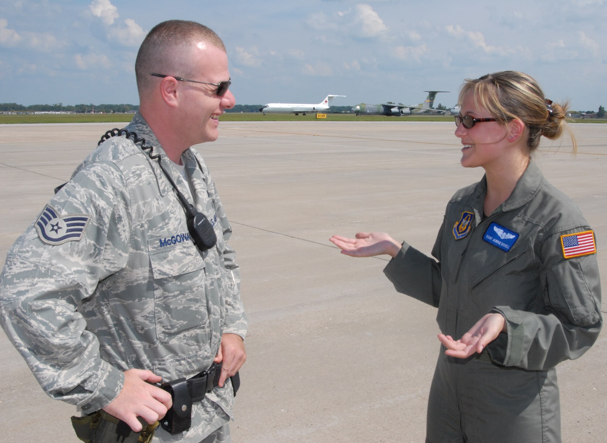 Air Force Reservist Staff Sgt. Tyler McGowan, with security forces, listens to Staff Sgt. Aubrie Miskell, 932nd Aeromedical Evacuation Squadron, talk about the training events for her squadron.  The 932nd Airlift Wing welcomed AE JAMBOREE participants from several states to train on the C-130, C-17 and KC-135 airplanes.  In the background is one of the unit's old C-9A planes that was retired.  (U.S. Air Force photo by Maj. Stan Paregien)