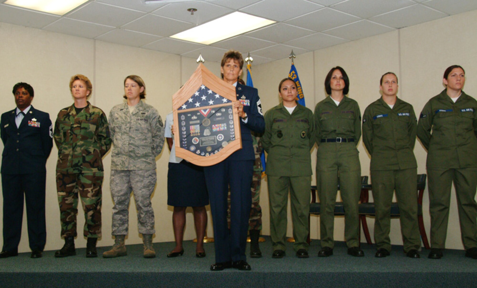 Newly retired Chief Master Sgt. June Robbins, stands in front of a group of Airmen wearing various Air Force uniforms during her retirement ceremony Aug. 15 at Eglin Air Force Base, Fla.  The uniforms and ranks were representive of the uniforms at that moment in time during the chief's Air Force career.  The shadowbox was passed to each Airmen on stage as the narrator explained the chief's career progression.  The chief ended her 30-year career as the 53d Test Management Group's top enlisted.  Photo by Staff Sgt. Samuel King Jr.