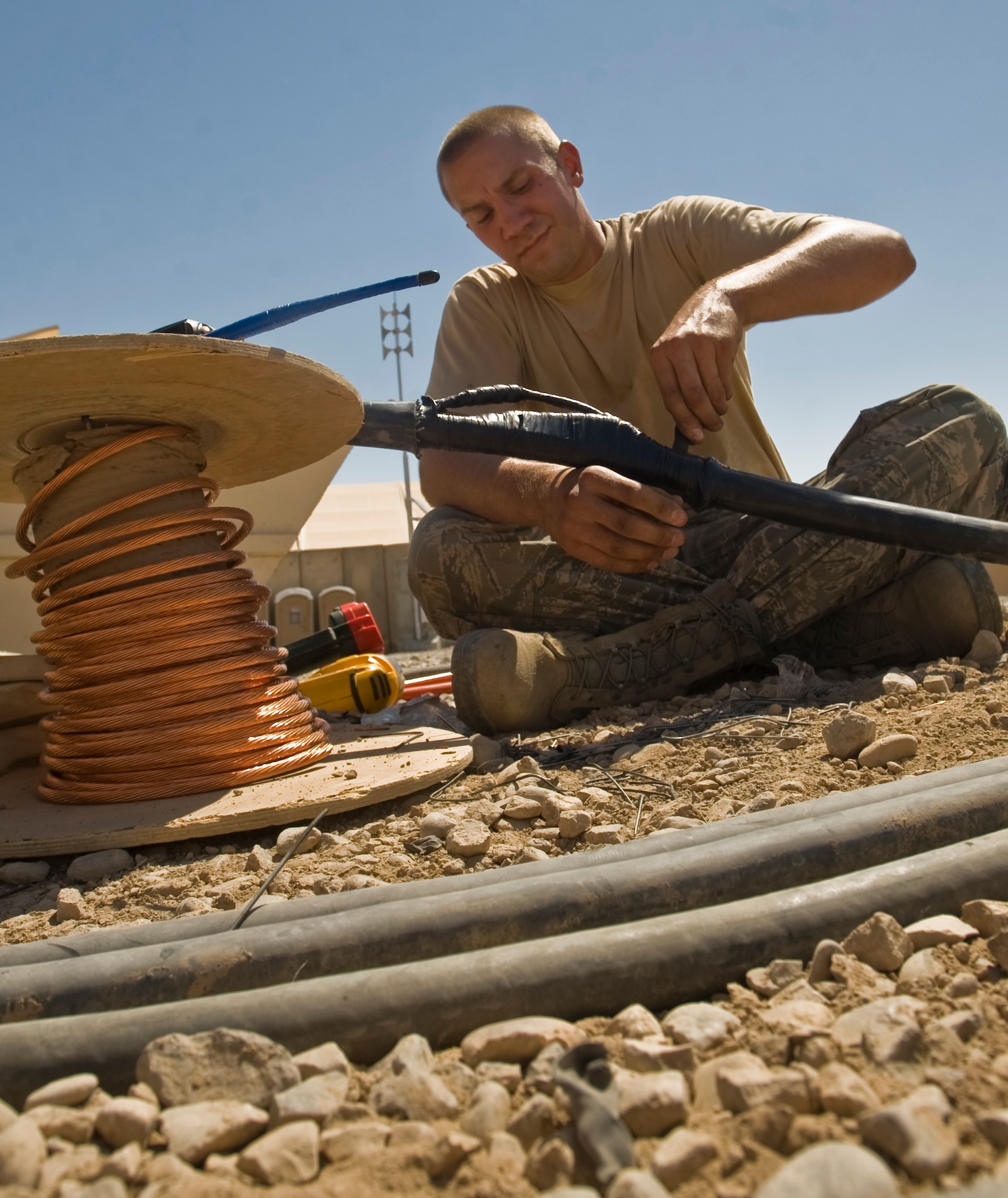 ALI BASE, Iraq -- Staff Sgt. Christopher Holman, 407th Expeditionary Civil Engineer Squadron electrician, wraps electrical tape around power cables Aug. 15, 2008. Power cables attached to the shelter housing the Predators recently caught fire and were replaced by electricians of the 407th ECES in five hours. The Predators are vital to the Global War on Terrorism, and must be kept cool and ready to go while not flying. Sergeant Holman is deployed from Malmstrom Air Force Base, Mont. (U.S. Air Force photo/Airman 1st Class Christopher Griffin)