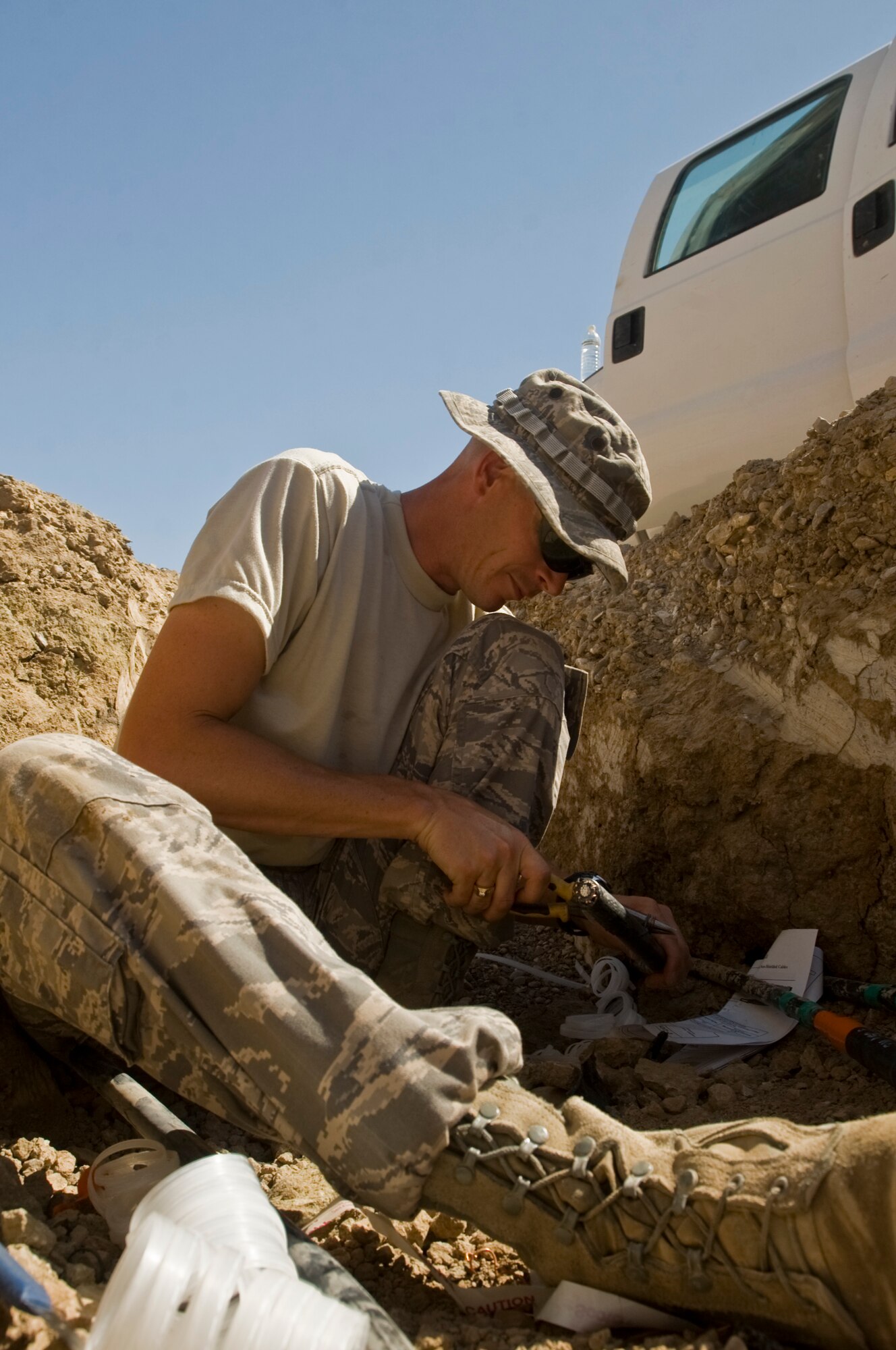 ALI BASE, Iraq -- Tech. Sgt. Clayton Schoepflin, 407th Expeditionary Civil Engineer Squadron electrical systems, cuts insulation off of a distribution line Aug. 15, 2008. Airmen of the 407th ECES are rerouting a power supply line that will soon feed the new mini base exchange here. Once complete, the BX will open and allow the entire base populace the opportunity to shop at two locations instead of just one. Sergeant Schoepflin is deployed from F.E. Warren Air Force Base, Wyo. (U.S. Air Force photo/Airman 1st Class Christopher Griffin)