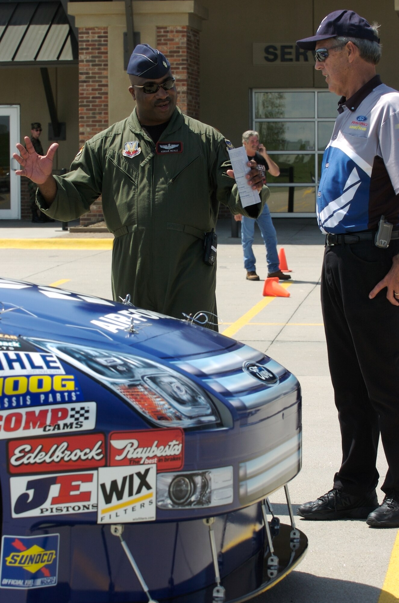 Maj. Adrian Beale (left) talks to Ron Mullins about the Brothers No. 21 Air Force Ford Fusion on display at the Dillon Brothers Harley-Davidson for Air Force Week in the Heartland Aug. 14 in Omaha, Neb. Mr. Mullins is the show car operator for the Wood Brothers. He works with recruiters to show the car to the public 10 months out of the year. The Air Force car and the Air Force Orange County Chopper were on display together. Major Beale is with the 55th Wing at Offutt Air Force Base, Neb. (U.S. Air Force photo/Lance Cheung)