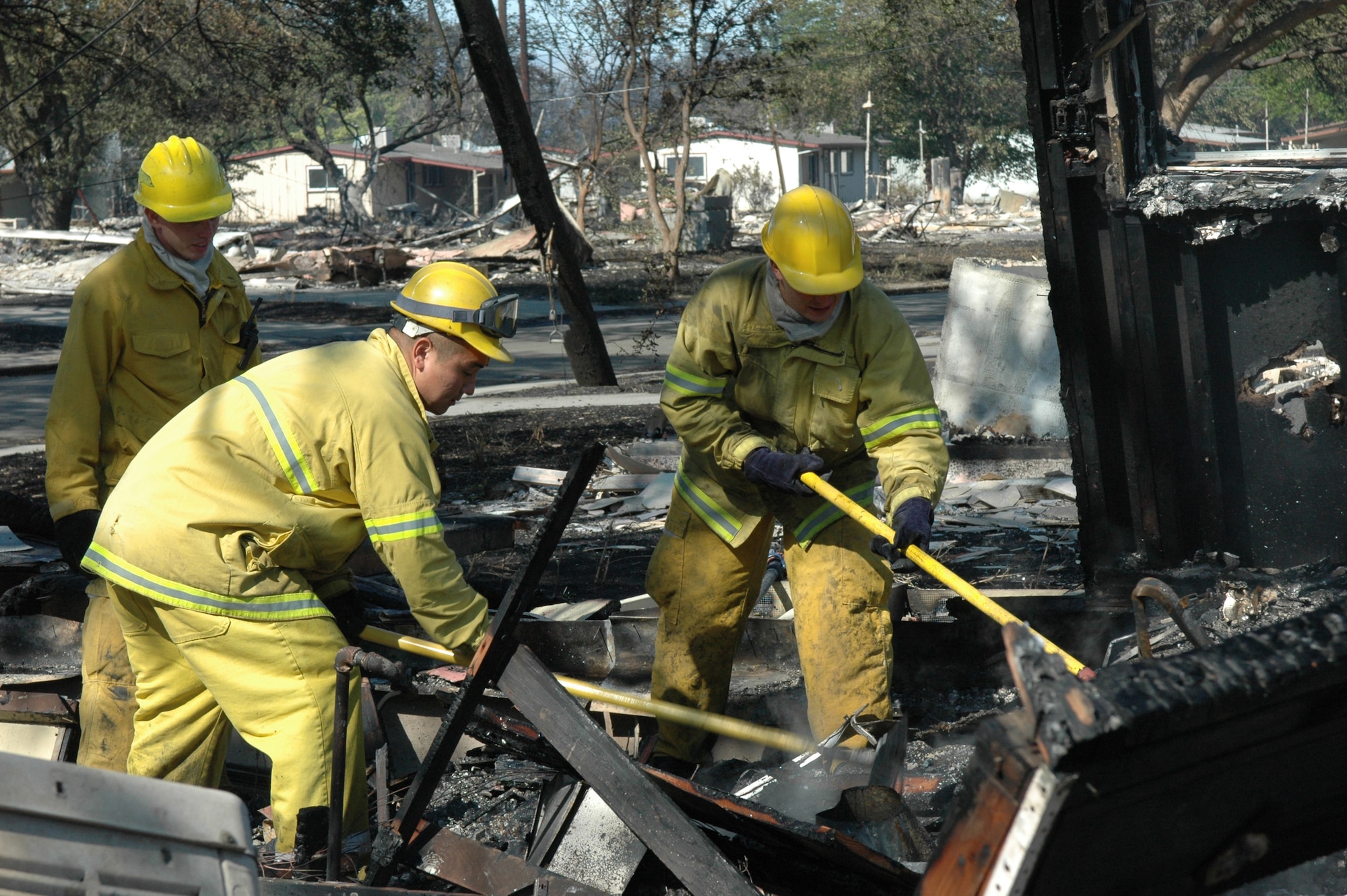 Staff Sgt. Jason Rich, a 60th Civil Engineering Squadron Fire Department crew chief,left, and firefighters Airmen 1st Class Spencer Snodgrass and Matthew Weber work to extinguish leftover hot spots following an eight-alarm fire that started adjacent to the base Aug. 16. (U.S. Air Force photo/Senior Airman Shaun Emery)