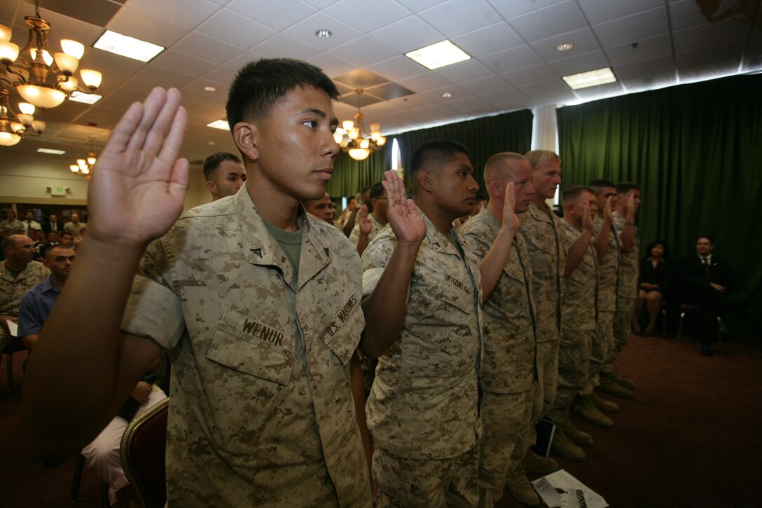 Indonesian native Lance Cpl. Hero Dengah (formally Wenur), a rifleman with Company G, 2nd Battalion, 25th Marine Regiment, recites the “Oath of Allegiance” with 23 other Marines and sailors from 16 different, originating countries during the first ever naturalization ceremony held on base, at the Combat Center’s Officer’s Club Aug. 19.
