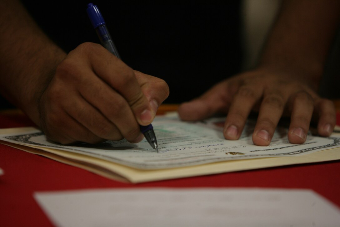 One of 24 Marines and sailors signs his naturalization papers during the first ever naturalization ceremony held at the Combat Center’s Officer’s Club Aug. 18.