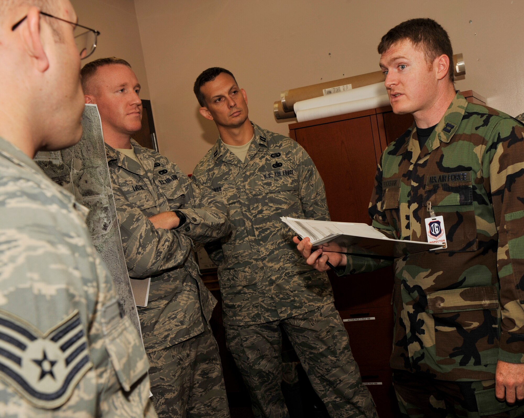 MOODY AIR FORCE BASE, Ga -- Airmen with the 23rd Communications Squadron listen as Capt. Michael Brockbank, Air Combat Command inspection team member, evaluates the CS Plans and Programs Flight here Aug. 18. Captain Brockbank discusses the contents of one of the unit’s binders as part of the ACC Unit Compliance Inspection. (U.S. photo by Senior Airman Schelli Jones)