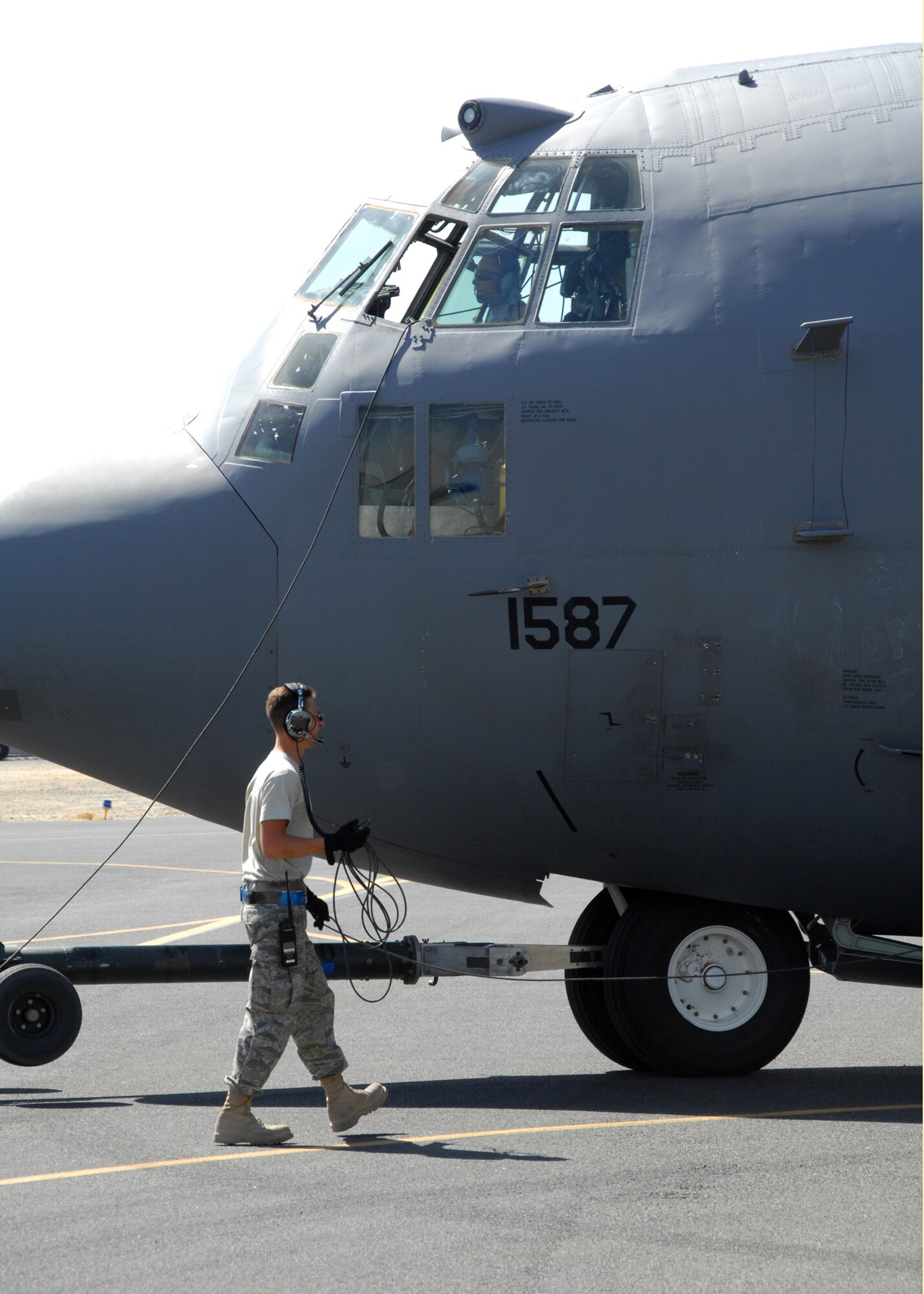 SOUTHWEST ASIA -- Staff Sgt. Dustin Krueger (bottom) and Airman 1st Class Jonathan Croft, both assigned to the 386th Expeditionary Aircraft Maintenance Squadron, guide an EC-130 Compass Call assigned to the 43rd Expeditionary Electronic Combat Squadron into its designated parking spot on Aug. 15 at an air base in Southwest Asia. The 43rd EECS just completed their 2,500th Operation Iraqi Freedom combat sortie. Since the squadron’s first OIF deployment in March 2004, the 43rd EECS has flown more than 17,500 mishap free combat hours providing electronic combat coverage to coalition troops operating in the OIF theater of operations. Sergeant Krueger and Airman Croft are both deployed from Davis-Monthan Air Force Base, Ariz. (U.S. Air Force photo/Tech. Sgt. Raheem Moore)