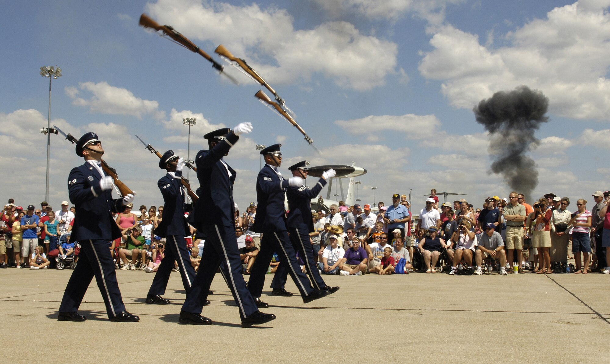 The U.S. Air Force Honor Guard Drill Team performs for a crowd, as bombs explode in the background, during an air show Aug. 16 at Offutt Air Force Base, Neb., presented in celebration of Air Force Week in Omaha, Neb. The drill team is the traveling component of the Honor Guard and tours worldwide representing all Airmen while showcasing Air Force precision. (U.S. Air Force photo by Senior Airman Dan DeCook)