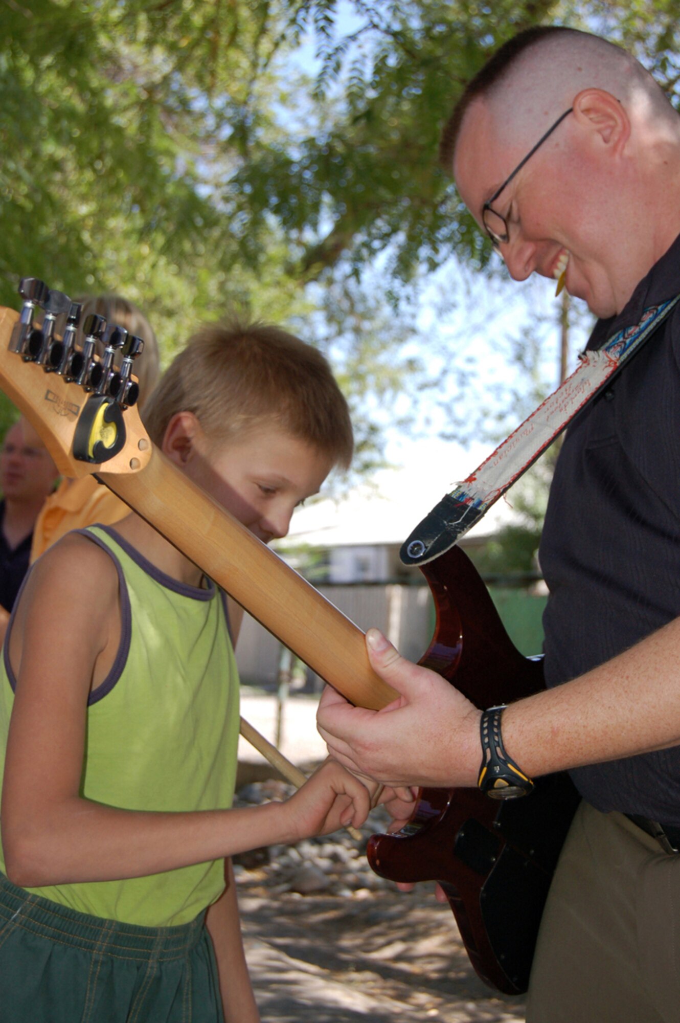 MANAS AIR BASE, KRYGYZ REPUBLIC--Staff Sgt. Chad Bailey, lead guitarist with the Air Forces Central Band "Sirocco," shows a Kyrgyz child the chords during a performance at the Najesda Center Orphanage in the Kyrgyz Republic Capitol of Bishkek. The band was on a ten day tour to Manas AB where they played at eight schools, villages and orphanages as well as at the U.S. Embassy and on base. (Air Force photo / Senior Master Sgt. Patrick J. McCracken)