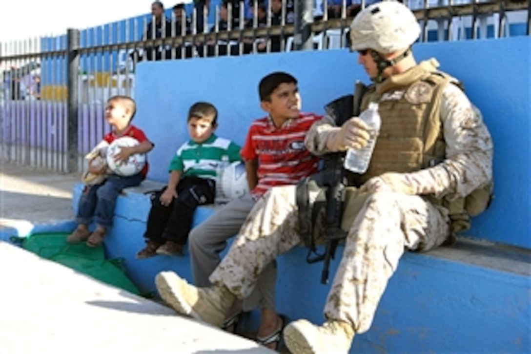 U.S. Army Chief Warrant Officer 2 Donald R. Rieg speaks with Iraqi children during a soccer tournament in Ramadi, Iraq, Aug. 13, 2008. Rieg is assigned to 1st Battalion, 9th Regiment, Regimental Combat Team 1, which sponsored the tournament. 