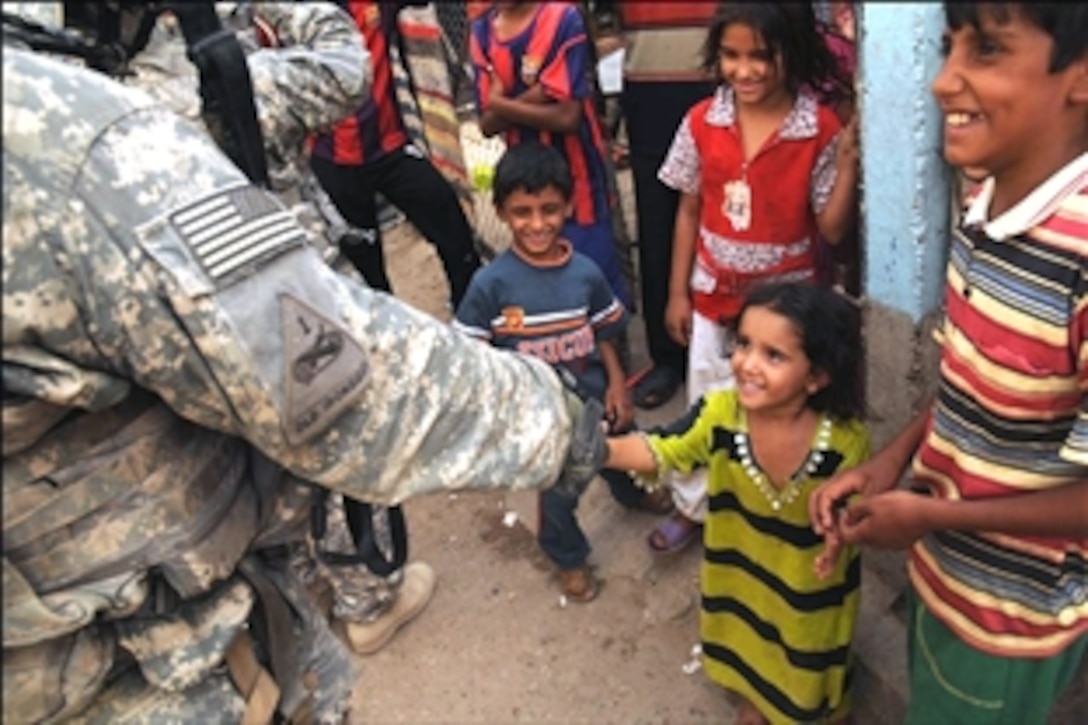 A U.S. Army soldier shakes the hand of an Iraqi girl as he and his squad conduct a patrol through the Muhalla 525 neighborhood of the Sadr City district of Baghdad, Iraq, Aug. 12, 2008. The soldiers are assigned to Company R, 1st Battalion, 6th Infantry Regiment.
