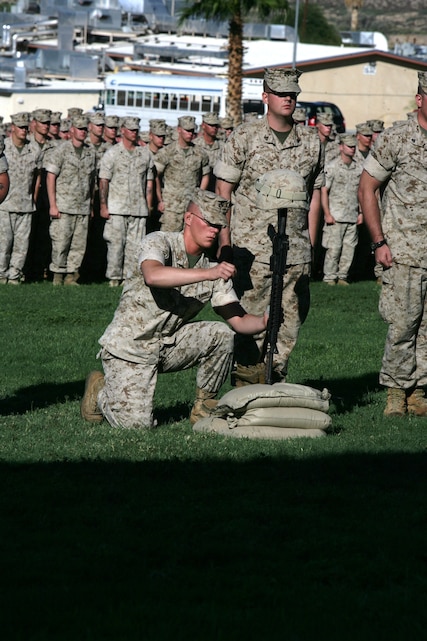 Lance Cpl. Jason Altmann, Company F, 2nd Battalion, 24th Marine Regiment, hangs the dog tags on the pistol grip for Cpl. Richard Nelson, who was killed in action April 14 in Iraq, during a memorial service Aug. 19 at Lance Cpl. Torrey L. Gray Field. Nelson and Lance Cpl. Dean Opicka were killed after their vehicle struck an improvised explosive device.