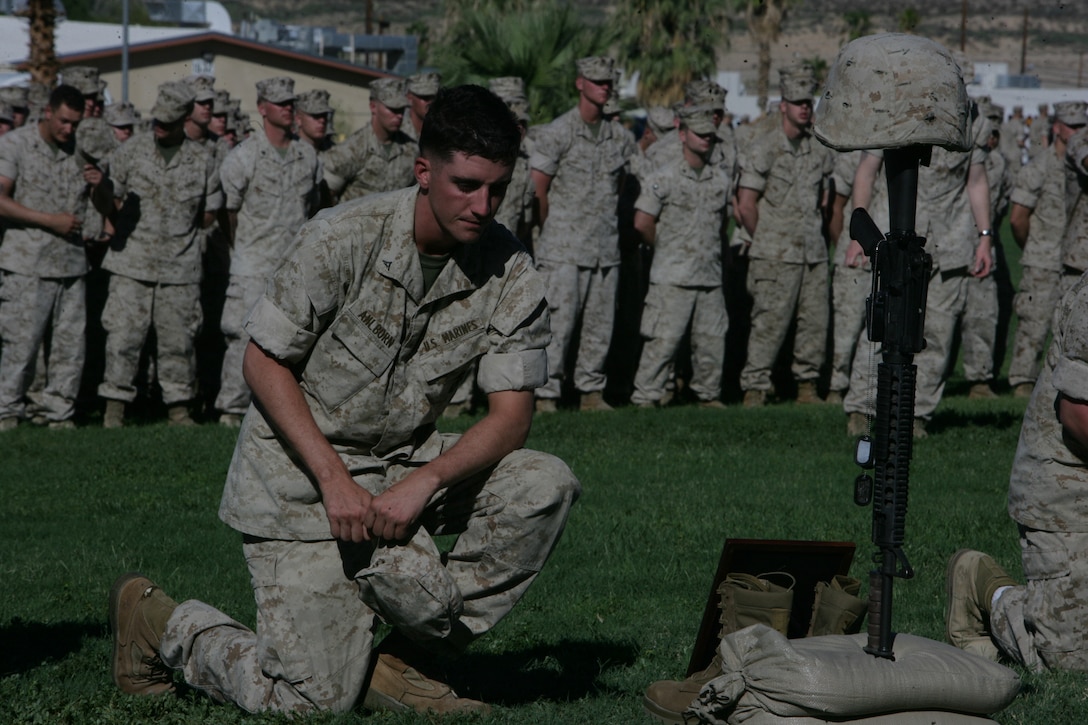 Lance Cpl. Jeffrey Ahlborn, Company E, 2nd Battalion, 24th Marine Regiment, kneels in front of the Soldier’s Crosses that represent Cpl. Richard Nelson and Lance Cpl. Dean Opicka, who were killed in action during their deployment to Iraq in a memorial service Tuesday at Lance Cpl. Torrey L. Gray Field. Nelson and Opicka were killed in action April 14 after their vehicle struck an improvised explosive device. As the ceremony came to a close, the Marines and sailors were given the opportunity to approach the Soldier’s Crosses and pay their last respects to Nelson and Opicka.