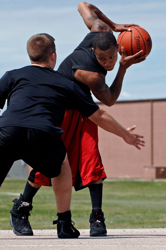 (Left) Airman Rocky Liberatore, 28th Bomb Wing emergency actions controller, guards Airman 1st Class Jerimie Egland, 28th Maintenance Squadron aerospace ground equipment technician, in a 3 on 3 basketball competition during the Ellsworth Olympic Picnic, Aug. 15. The picnic had multiple sporting events including: volleyball, canoe tug of war, dizzy bat racing and softball. (U.S. Air Force photo/Senior Airman Marc I. Lane)