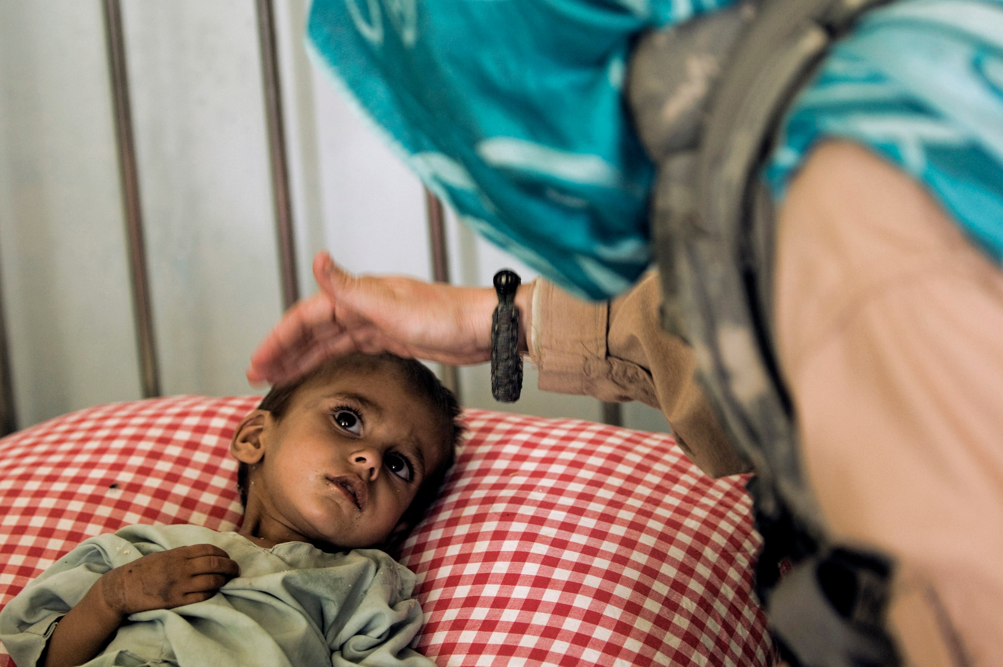 Senior Airman Felicita Torres-Perkins comforts a young Afghan girl suffering from malnutrition Aug. 10 at the Qalat Hospital in Qalat, Afghanistan.  The Airman is deployed from McGuire Air Force Base, N. J., and wears the scarf in an effort to honor the customs of this region of Afghanistan. (U.S. Air Force photo/ Master Sgt. Keith Brown)