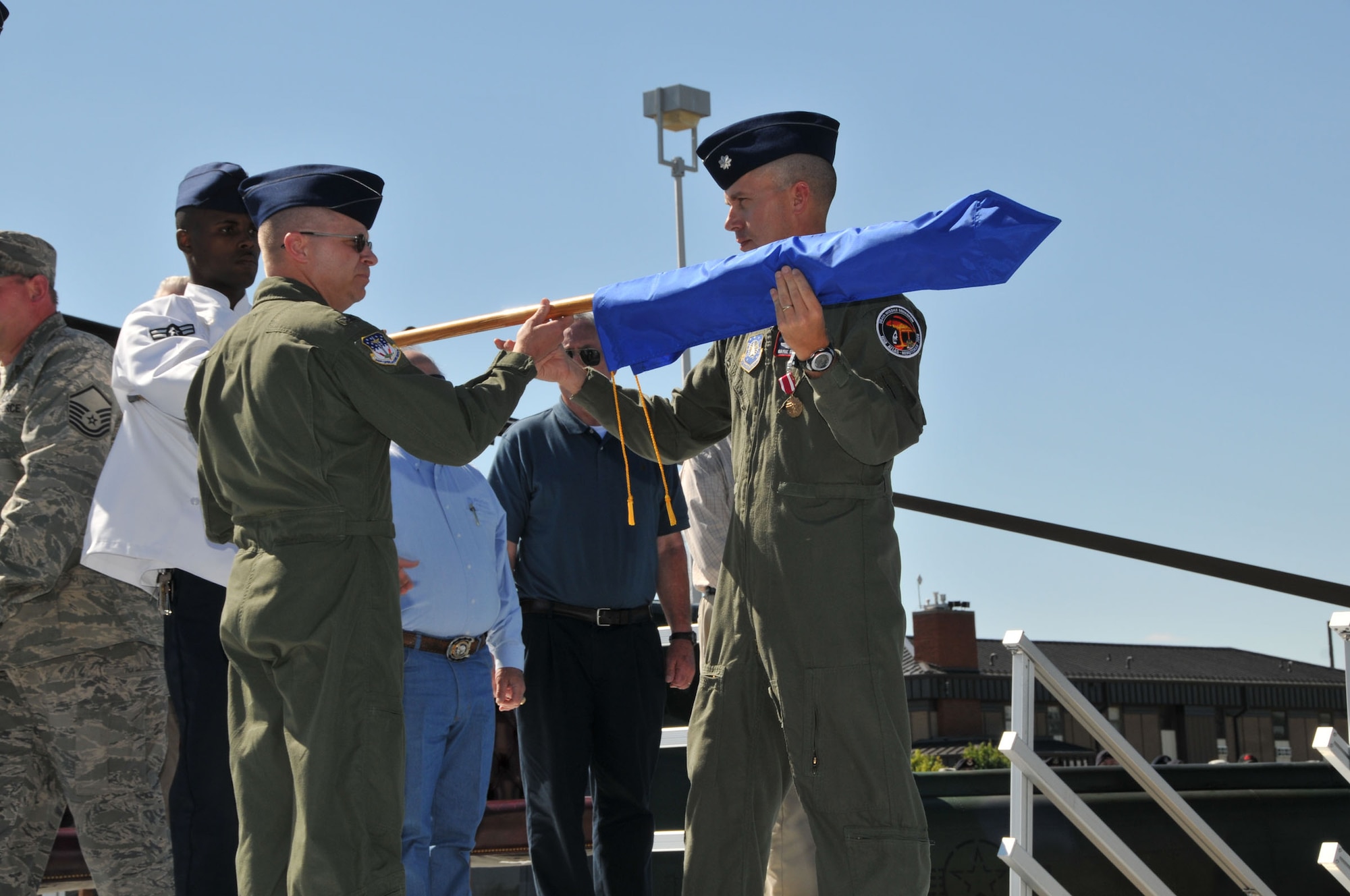 Airman 1st Class Michael Jordan, 564th Missile Squadron chef and the youngest member of the squadron, and Col. David Durgan, 341st Operations Group commander, hold the guidon while Lt. Col. Wayne Shaw, 564th MS commander, cases it during a ceremony to inactivate the squadron Aug. 15. The casing of a unit's guidon is a solemn act, steeped in military tradition. The unit's colors are furled for final time time and covered to signify the inactivation of the unit as well as the successful completion of its nuclear deterrent mission. (U.S. Air Force photo/John Turner)