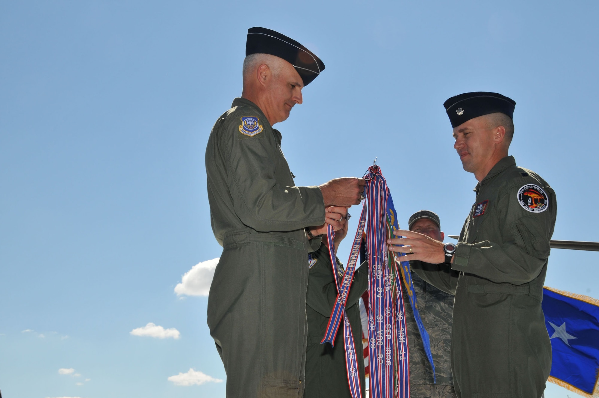 Maj. Gen. Roger Burg, 20th Air Force commander, adds the Outstanding Unit Award ribbon to the 564th Missile Squadron guidon after presenting the award to Lt. Col. Wayne Shaw, 564th MS commander, who looks on. The presentation preceeded the inactivation ceremony Aug. 15 at Medal of Honor Park. (U.S. Air Force photo/John Turner)