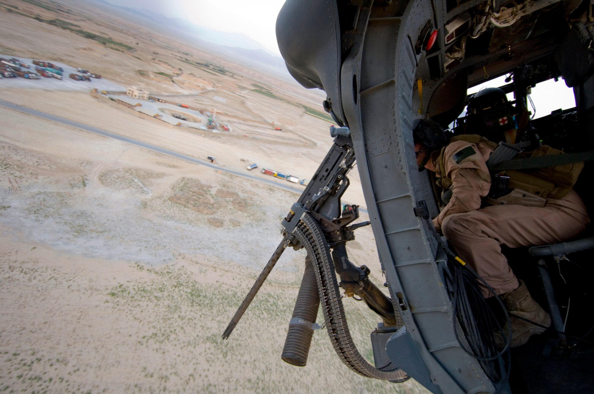 Senior Airman Ryan Ballinger looks out over Bagram Air Base, Afghanistan, Aug. 2 after take-off. Airman Ballinger is a 33rd Expeditionary Rescue Squadron gunner, and deployed from the 33rd Rescue Squadron at Kadena AB, Japan. (U.S. Air Force photo/Staff Sgt. Samuel Morse)