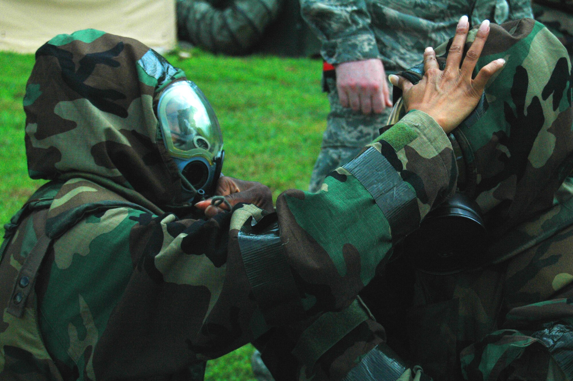 During the Operational Readiness Exercise, an alarm sounds initiating an order for all personnel to begin to suit up in their full chemical warfare gear, including gask masks which are to be checked for propper wear by a wingman.