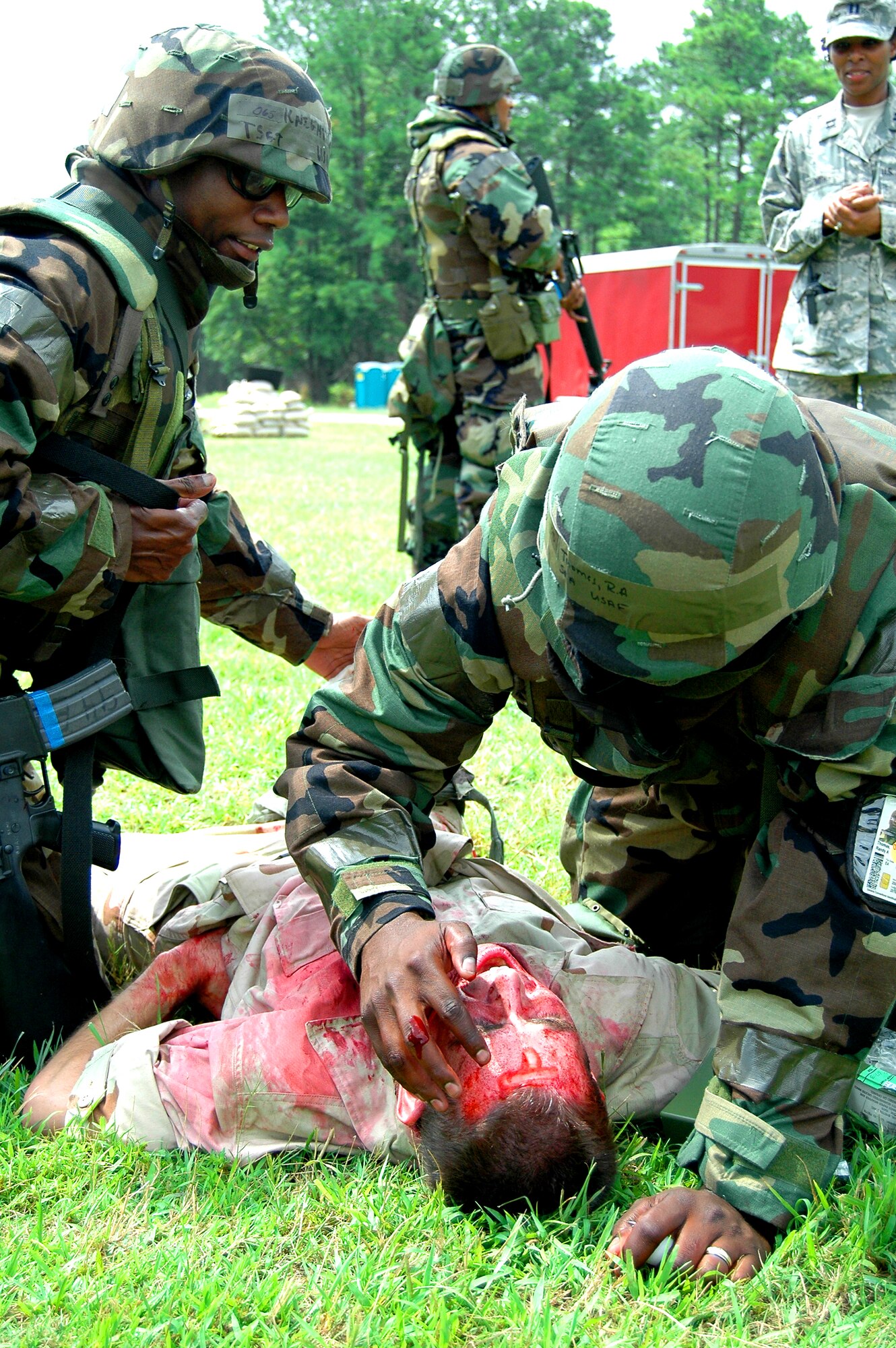 Senior Airman Randy A. Thomas, a member of the 94th Airlift Wing's Services Squadron, writes on the forehead of a simulated explosive victim, Senior Airman Stephen Z. Herbel of the 80th Aerial Port Squadron. Airman Thomas writes the letter "T" as an indicator that a tourniquet was used on the victim as well as the current date and time, after treating his wounds as much as possible as part of Self Aid Buddy Care protocol.