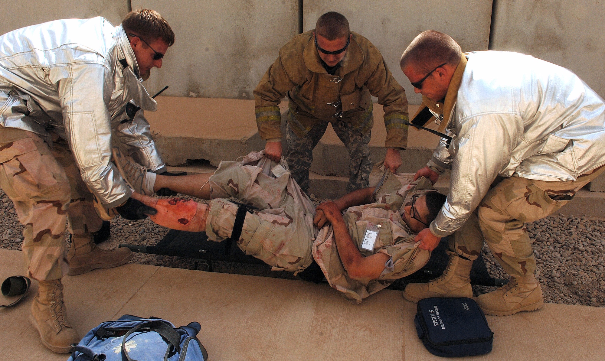 Senior Airman Adam Mercer, Army Spc. James Taylor and Senior Airman Aaron Huddle load a patient onto a stretcher during a mass accident response exercise Aug. 11 at Joint Base Balad, Iraq. More than 100 Airmen and Soldiers participated in the joint exercise ensuring first responders are ready for any situation at any time. The firefighters are assigned to the Joint Base Balad Fire Department here. Airman Mercer is deployed from Misawa Air Base, Japan, Specialist Taylor is deployed from Fort Bragg, N.C., and Airman Huddle is deployed from Andersen Air Force Base, Guam. (U.S. Air Force photo/Tech. Sgt. Richard Lisum) 
