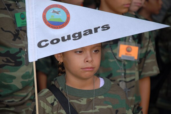 Teagan Lessord, 10, guidon bearer for the Cougars Flight waits to march to the C-17 to ‘take off’ on their deployment, during Operatin Hele On. Hele On in Hawaiian means move forward and the event provides Hickam’s youngest warriors a glimpse into what their parents go through as they prepare to deploy. (U.S. Air Force Photo/Staff Sgt. Erin Smith)