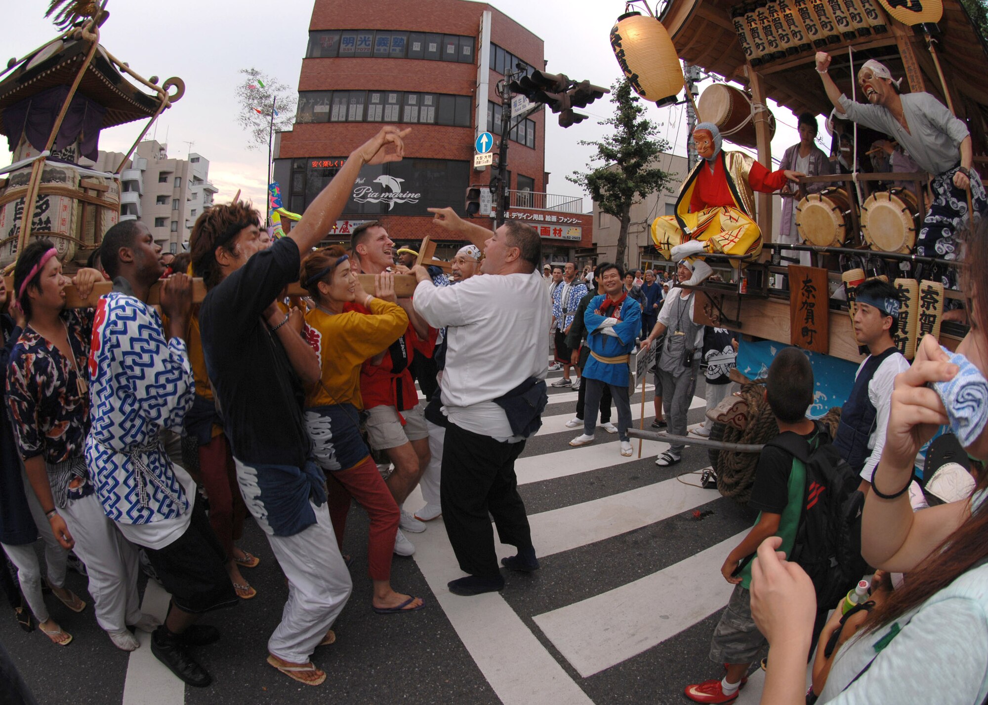 Military members from Yokota Air Base, Japan, cheer and carry a shrine in front of a mobile stage while Japanese and performers cheer during the Fussa Tanabata Festival Aug. 8 at Fussa City, Japan. The group carried the shrine from Shinmeisya Shrine to the Fussa City Hall. (U.S. Air Force photo/Airman 1st Class Jonathan Fowler) 